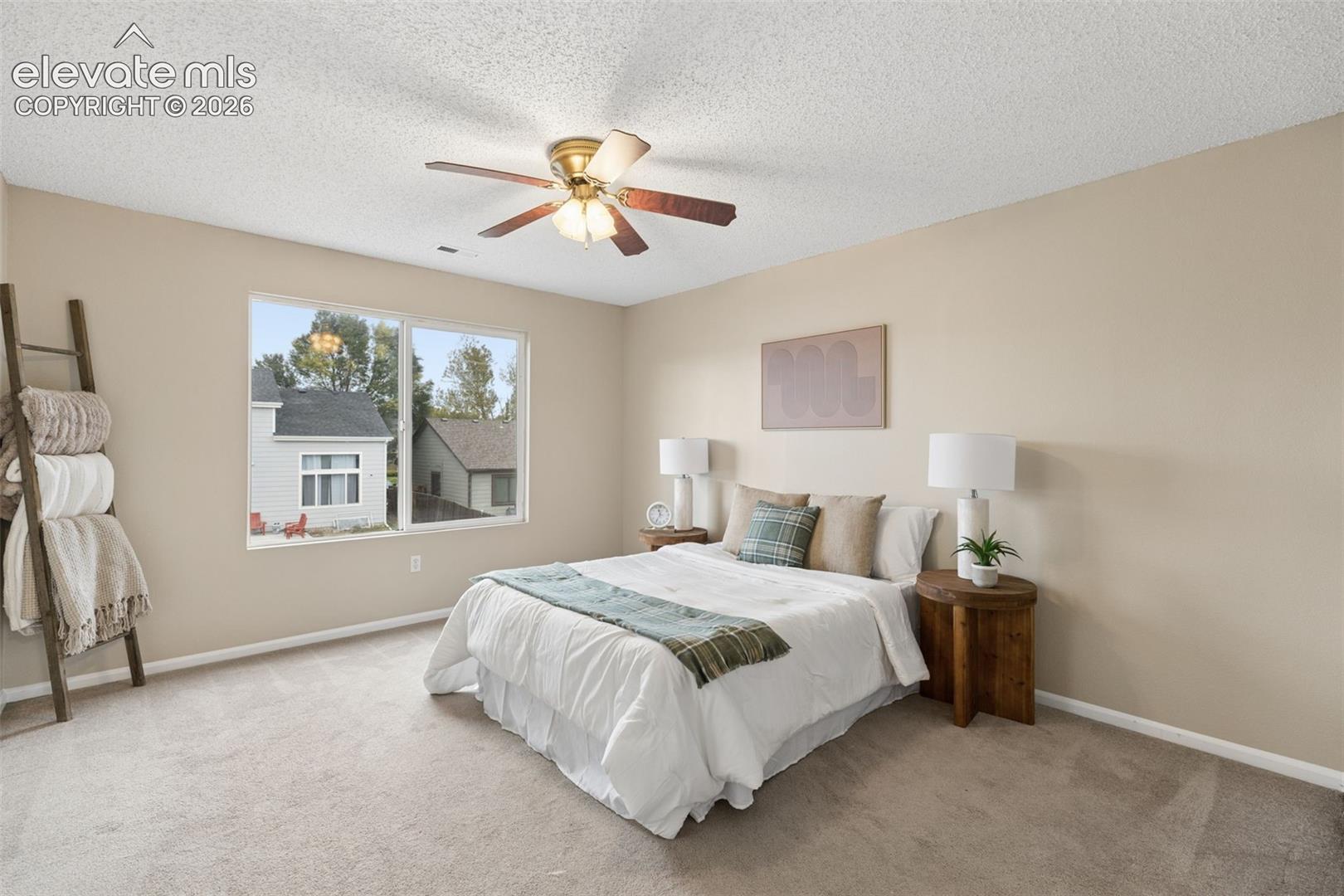 Neutral-toned room featuring wall-to-wall carpeting, a multi-pane window, and a ceiling fan with integrated lighting