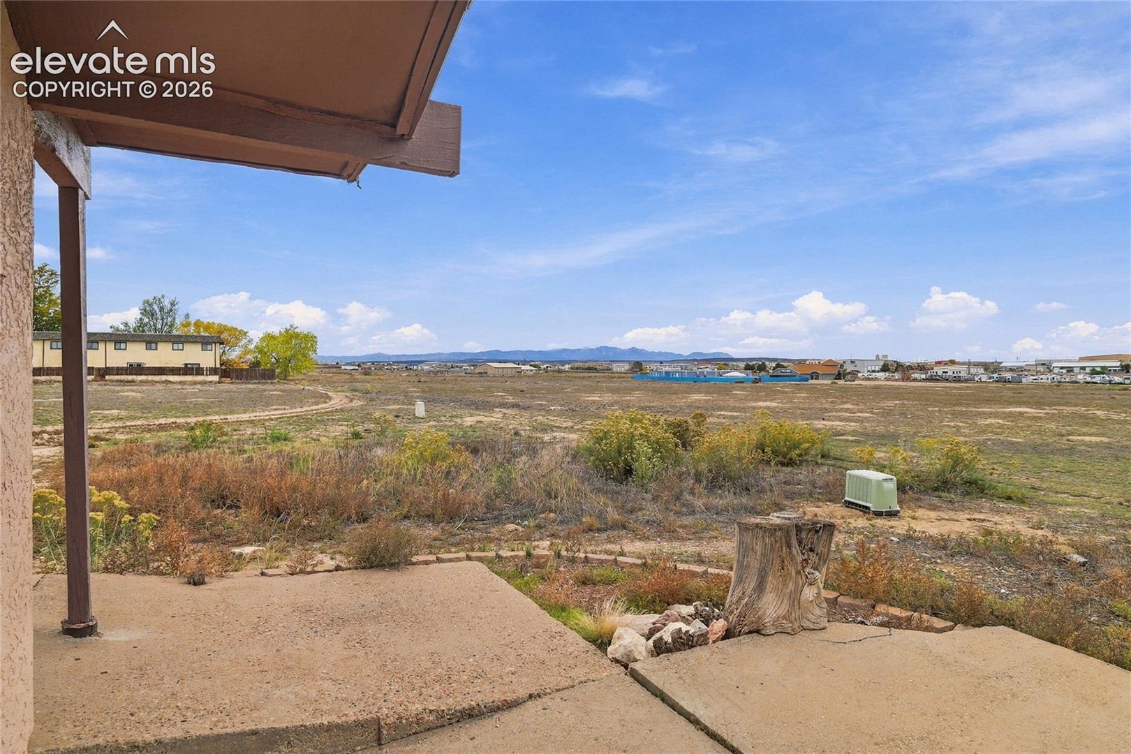 Covered concrete patio with open-air access to expansive exterior grounds and mountain range backdrop