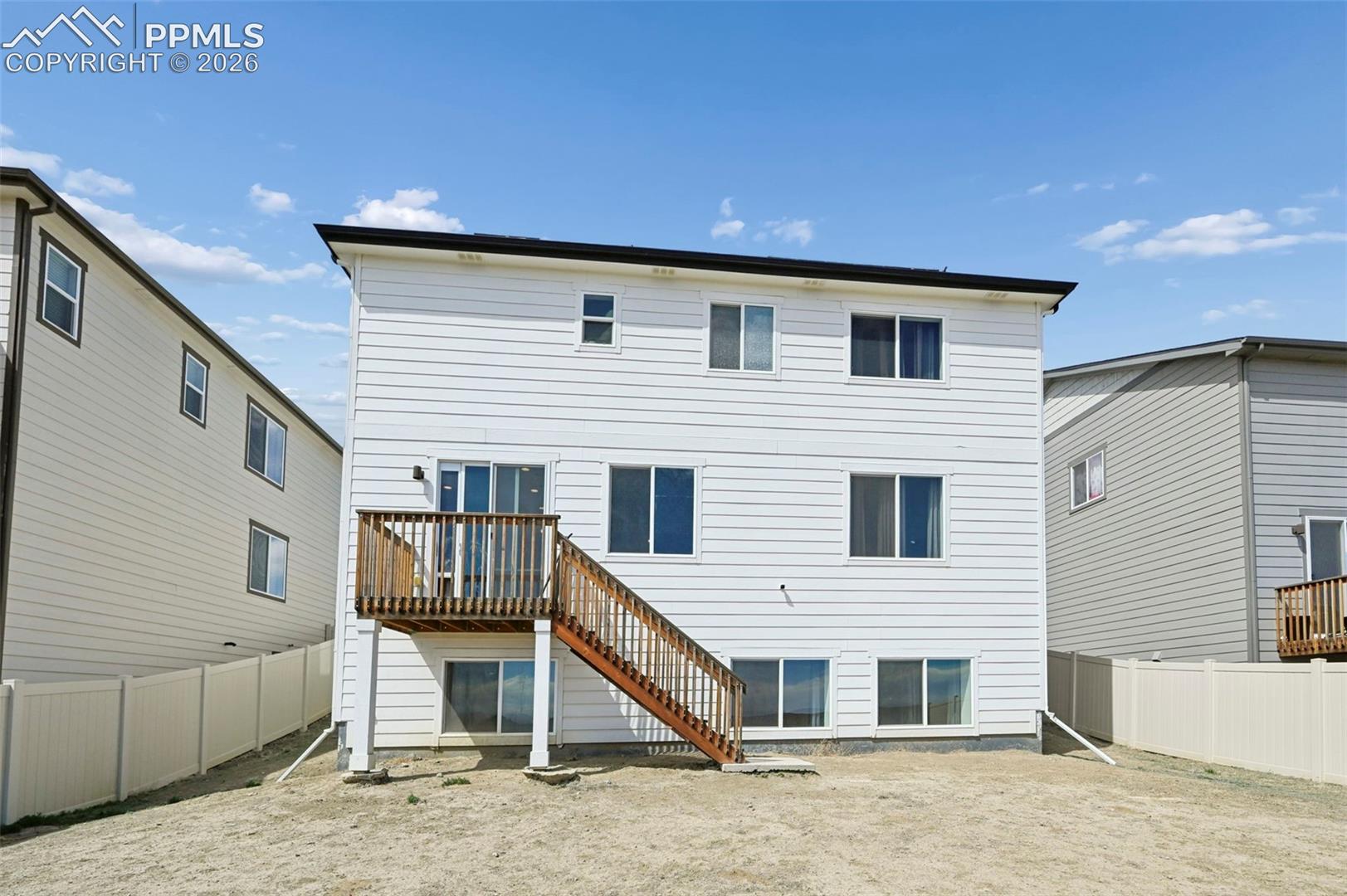 Rear exterior featuring white horizontal siding and a wood-finish deck with stairs