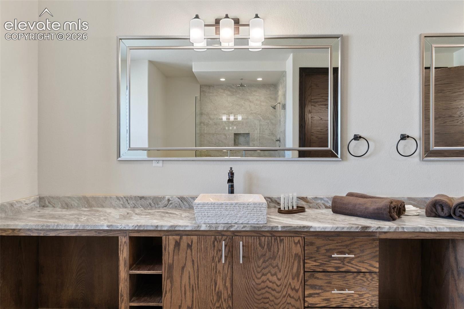 Dual vanity with a stone countertop, featuring a vessel sink and dark wood cabinetry