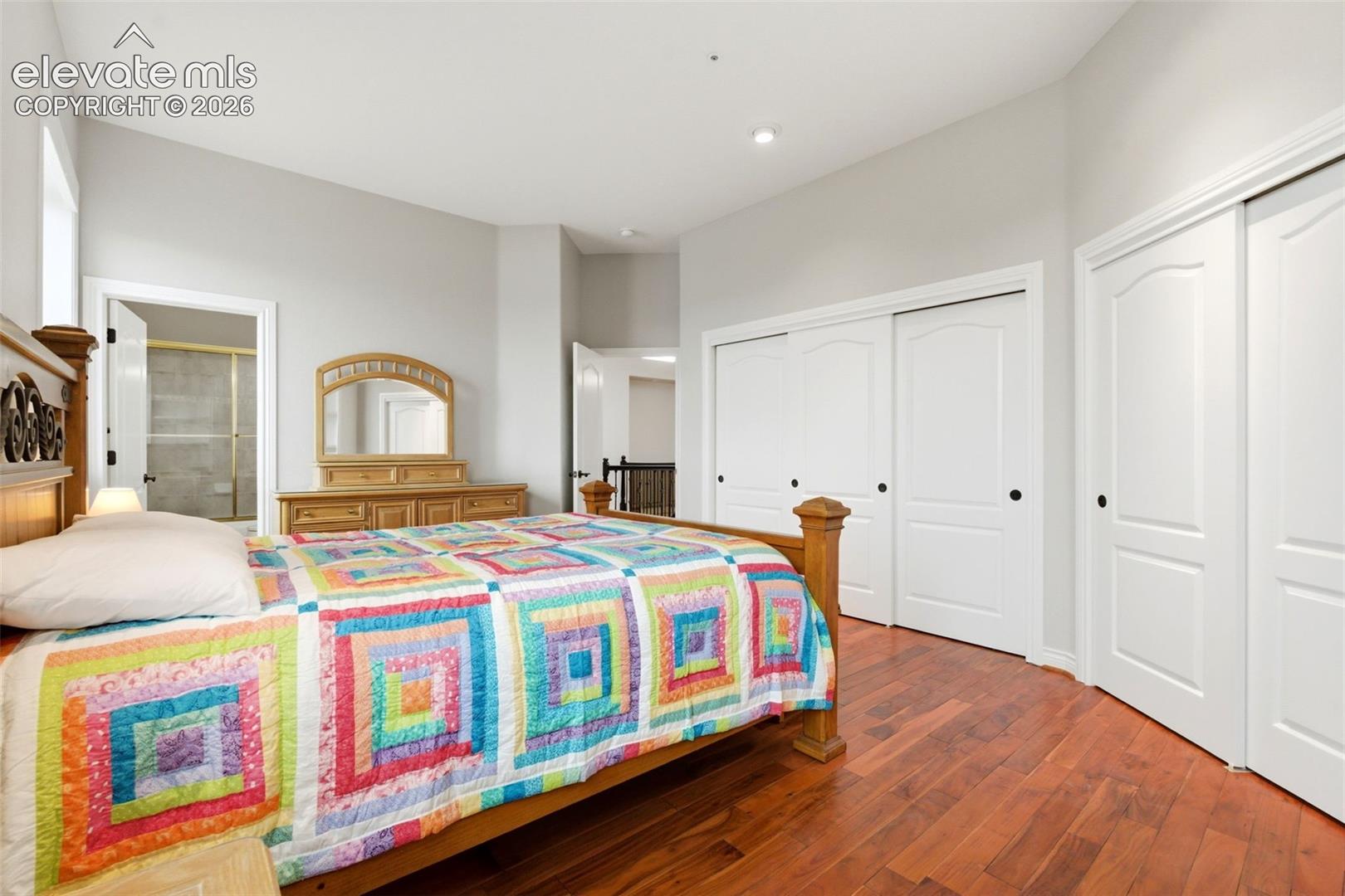 Hardwood flooring, recessed lighting, vaulted ceiling, sliding closet doors, and an en-suite bathroom featuring a glass-enclosed shower