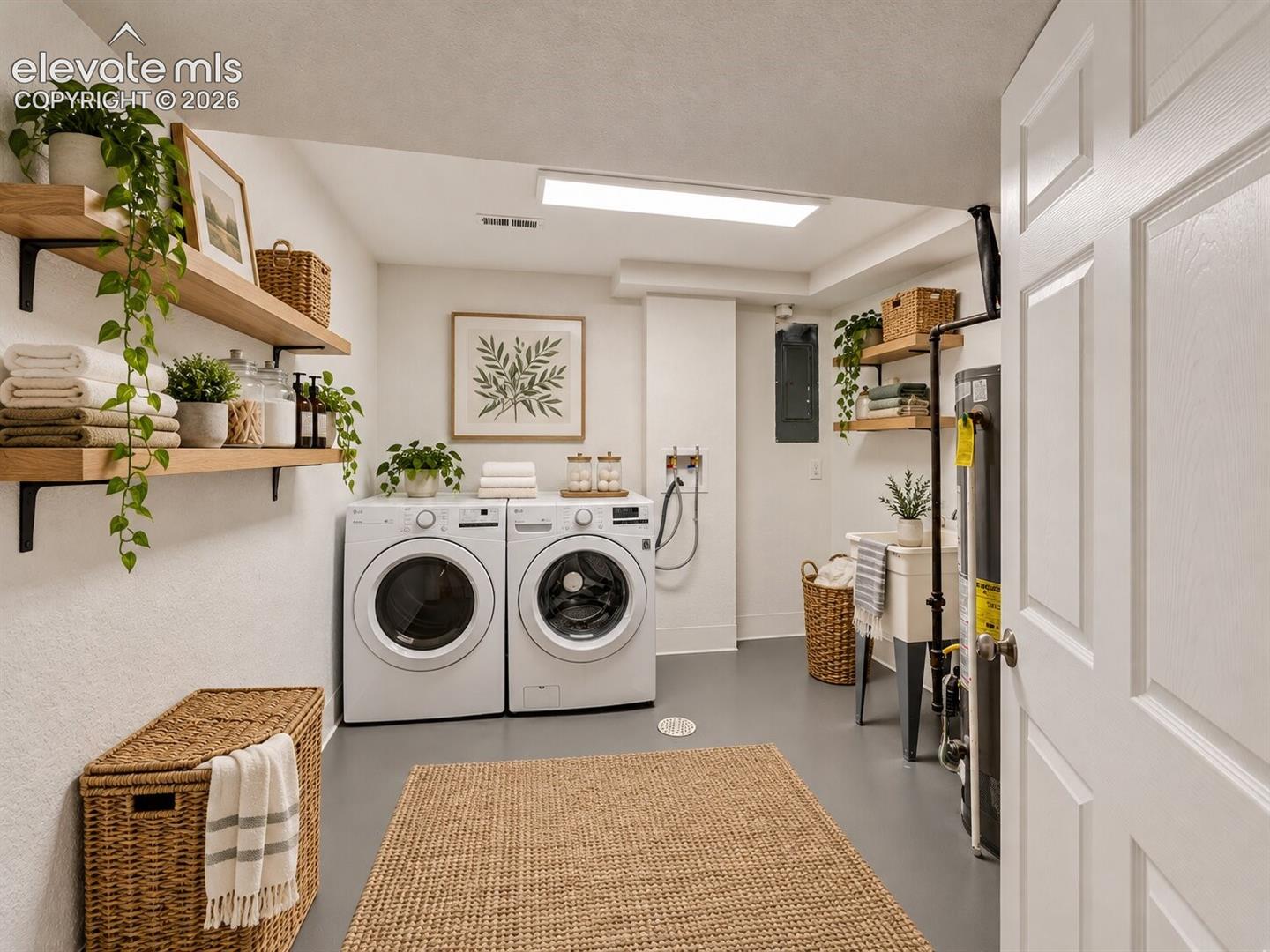 Laundry room featuring integrated washer and dryer hookups, utility sink, wall-mounted wood shelving, and flat-panel door. AI-Enhanced – furniture/decor digitally added