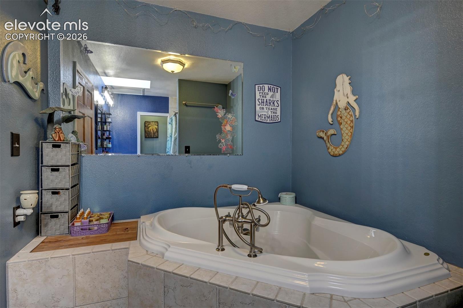 Built-in corner soaking tub with deck-mounted faucet, surrounded by tiled platform
