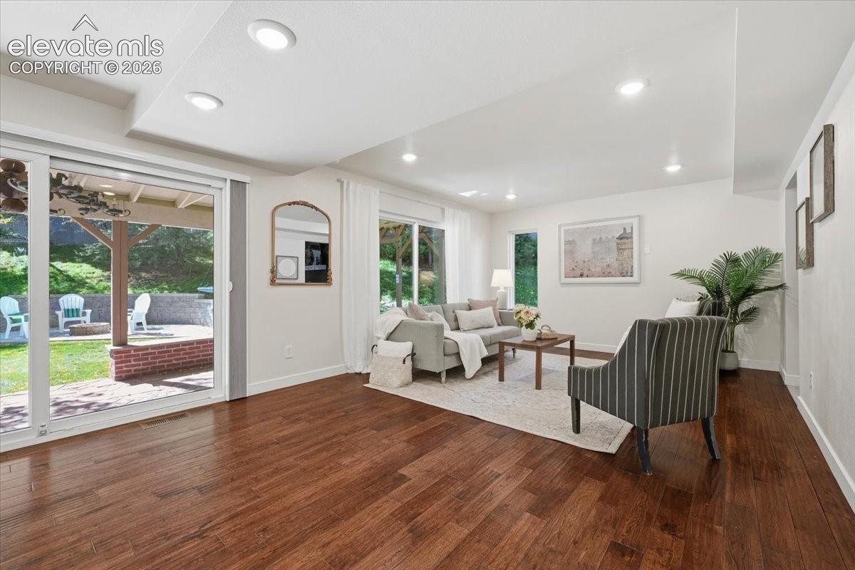 Wood flooring throughout, recessed lighting, and extra wide sliding glass doors leading to an outdoor brick patio