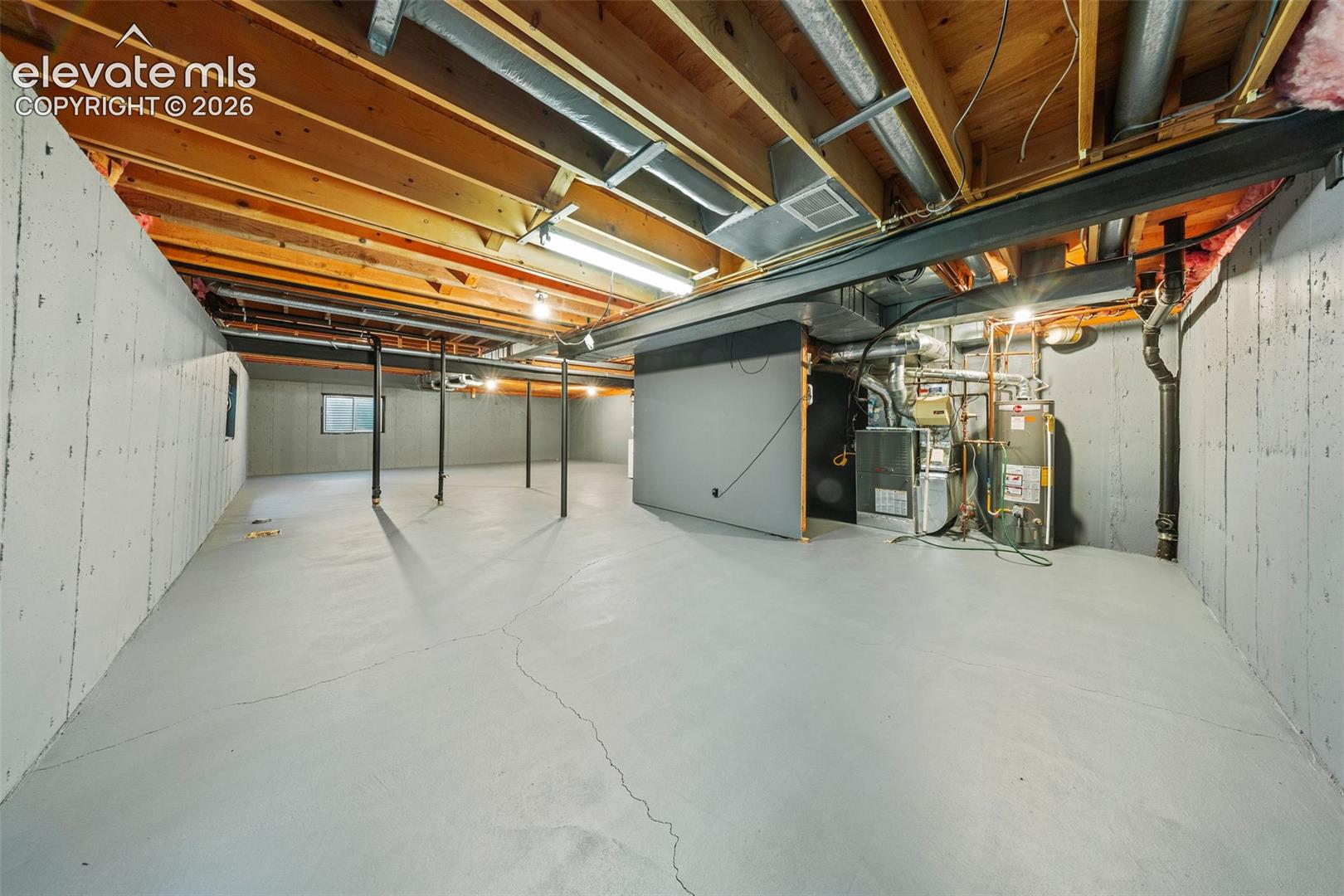 Unfinished lower level featuring exposed wood joist ceilings, painted concrete walls, painted concrete flooring, structural steel support columns, and an integrated mechanical system