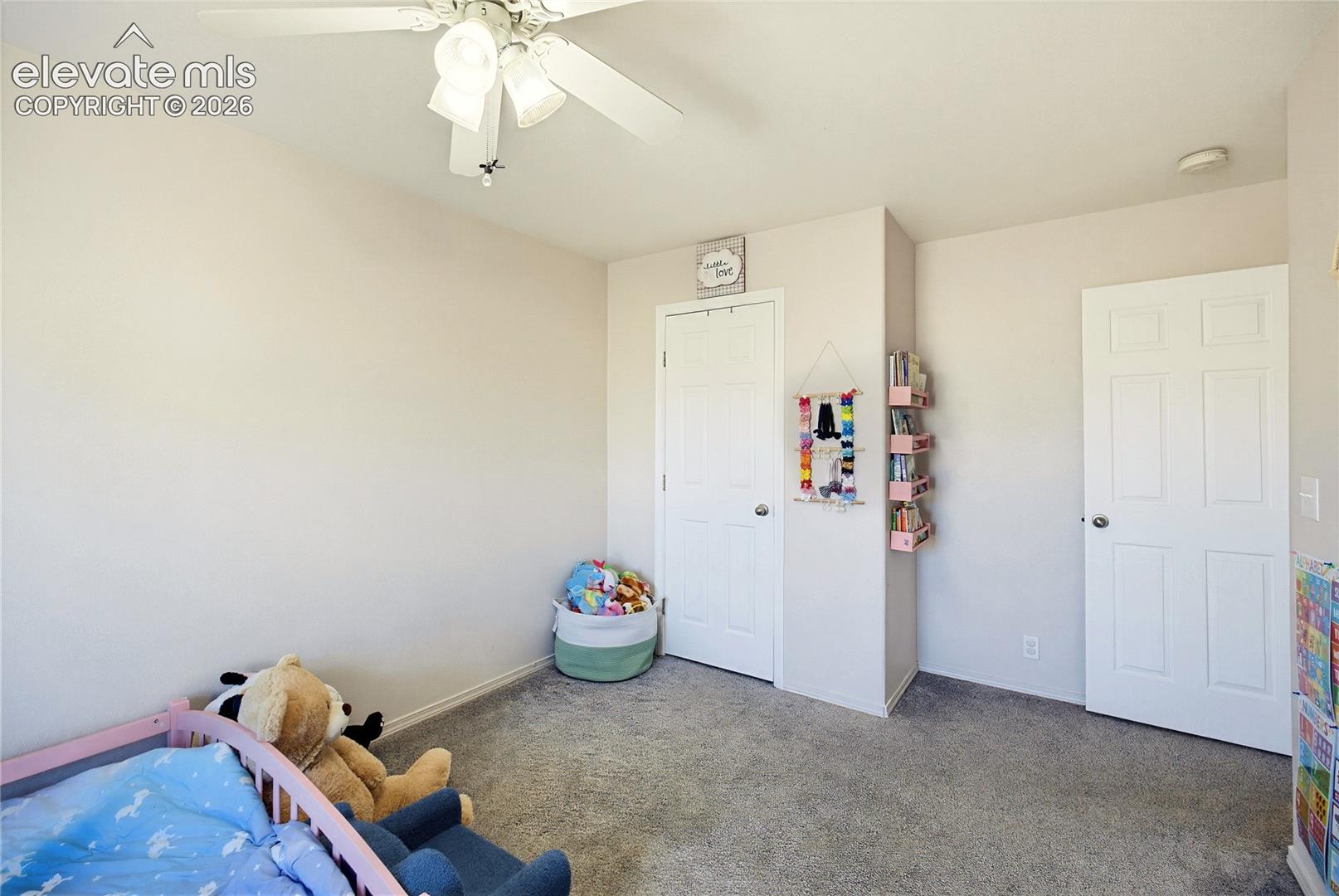 Neutral-toned walls, grey carpet, ceiling fan with integrated lighting, and white paneled doors