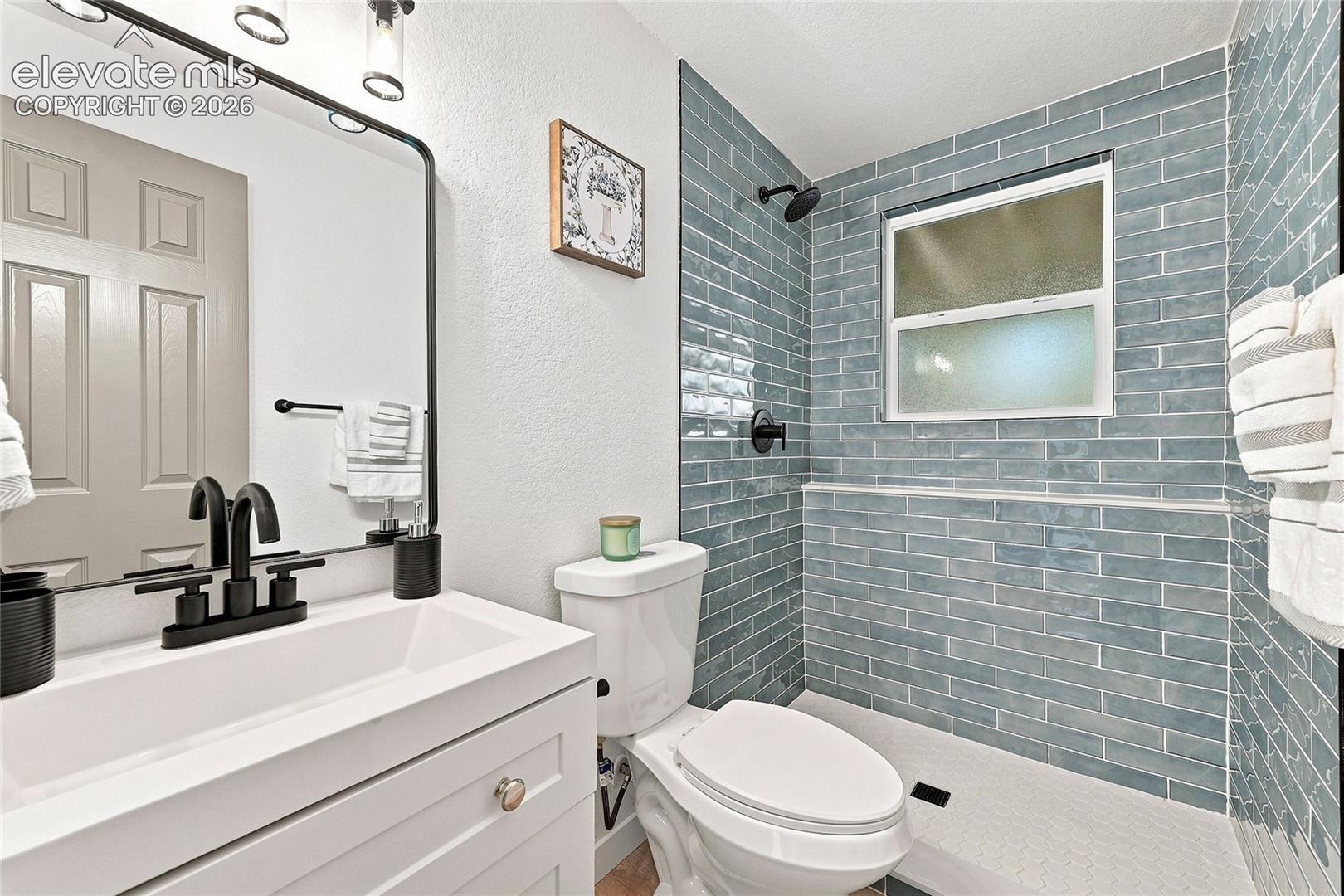 Modern bathroom featuring a vanity with integrated sink, matte black fixtures, and a rectangular mirror