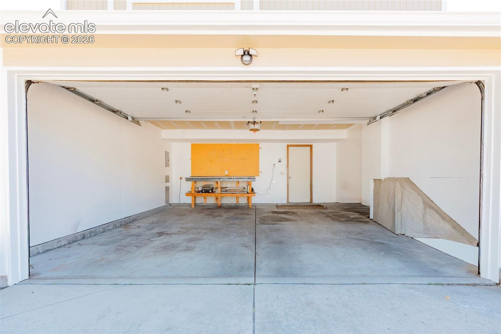 Spacious garage featuring a concrete floor, overhead lighting, and white painted walls