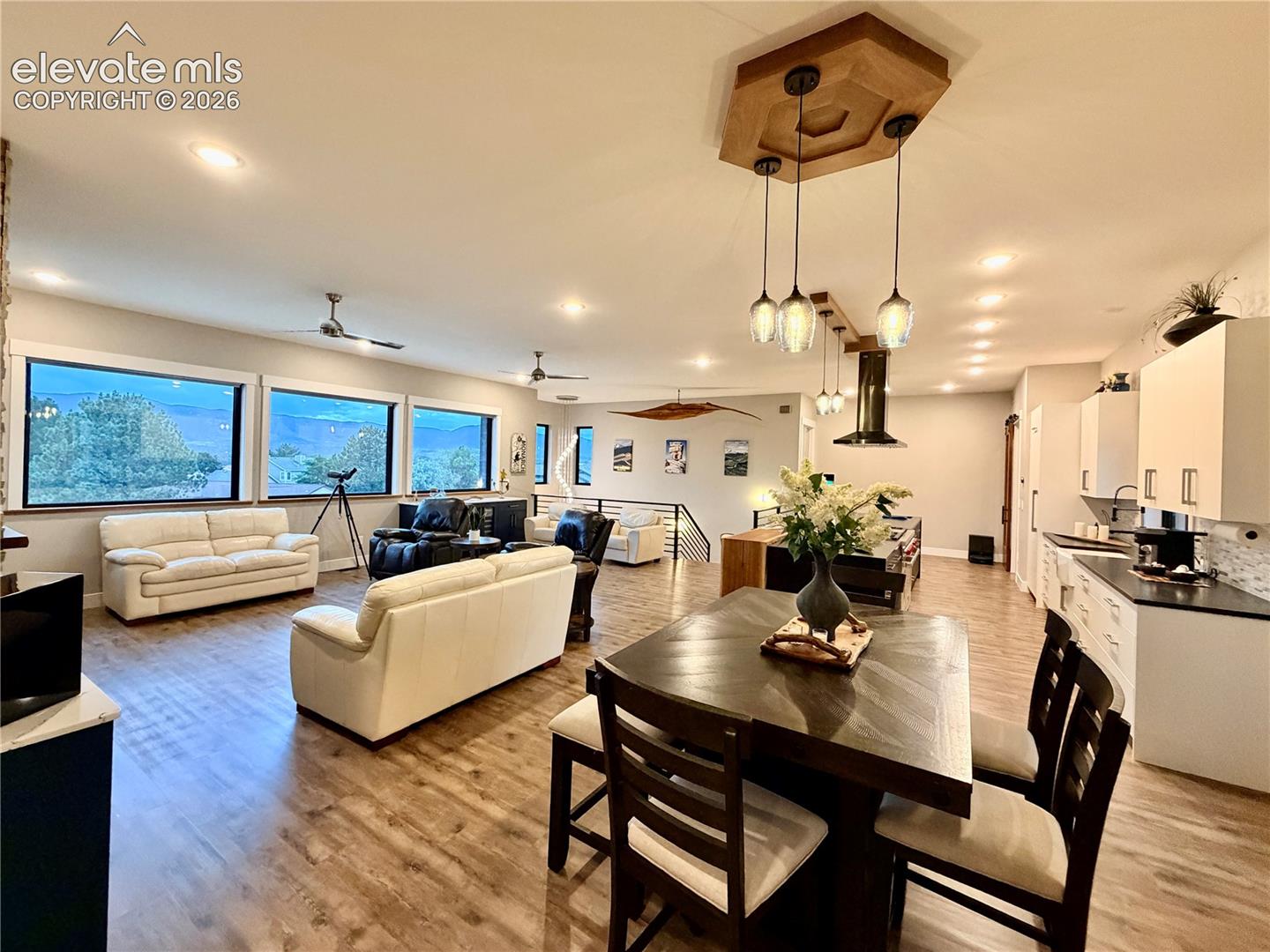 Open-concept living area with wood-finish flooring, recessed lighting, and multiple large windows