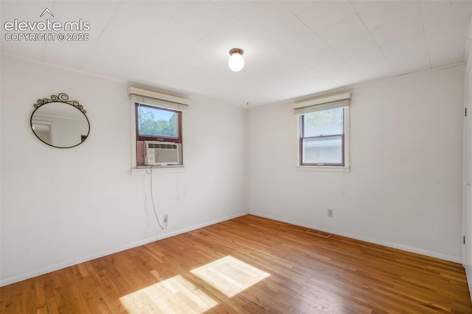 Hardwood flooring, white walls, and a ceiling-mounted light fixture
