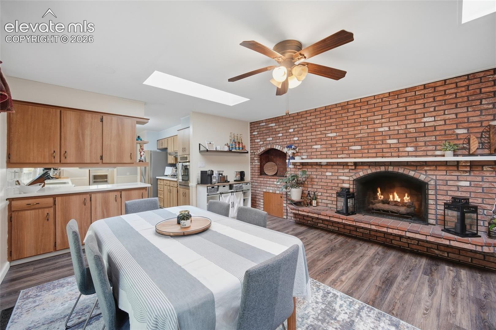 Full-height red brick fireplace with an arched hearth and integrated mantle, skylight, wood-finish flooring, and built-in cabinetry