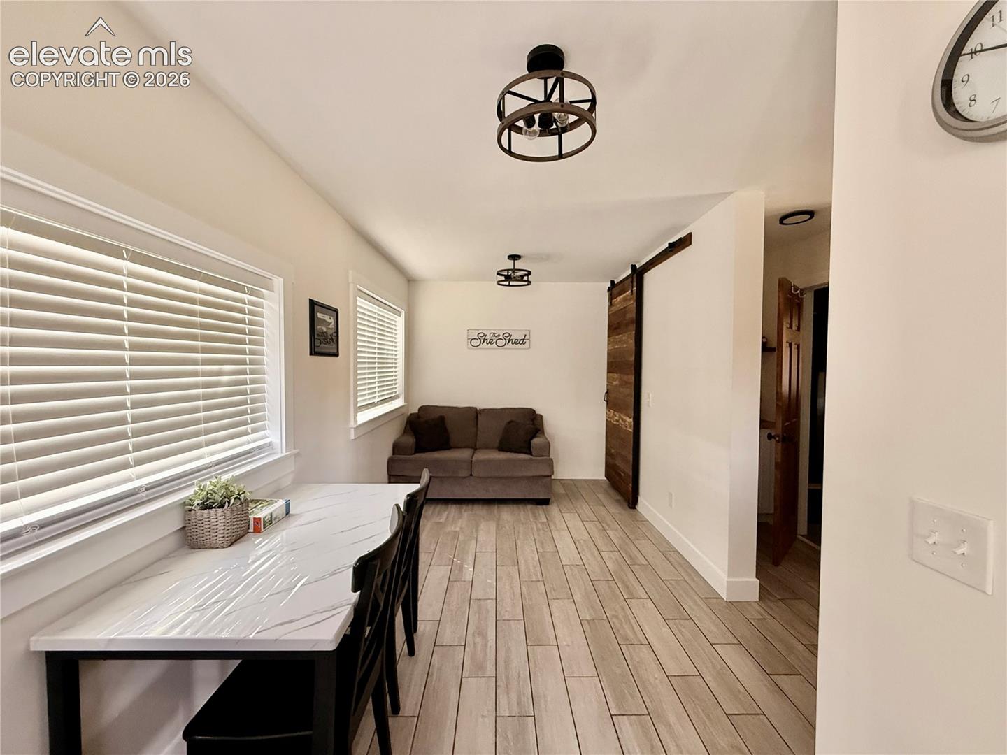 Wood-finish flooring throughout, white framed windows, and a sliding wood-panel barn door