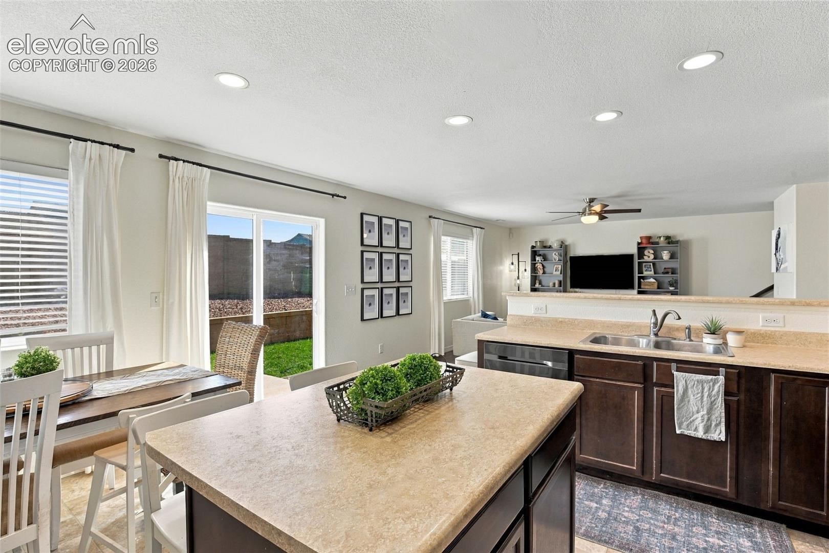 Kitchen featuring dark wood-finish cabinetry, a double basin stainless steel sink, and light-toned countertops