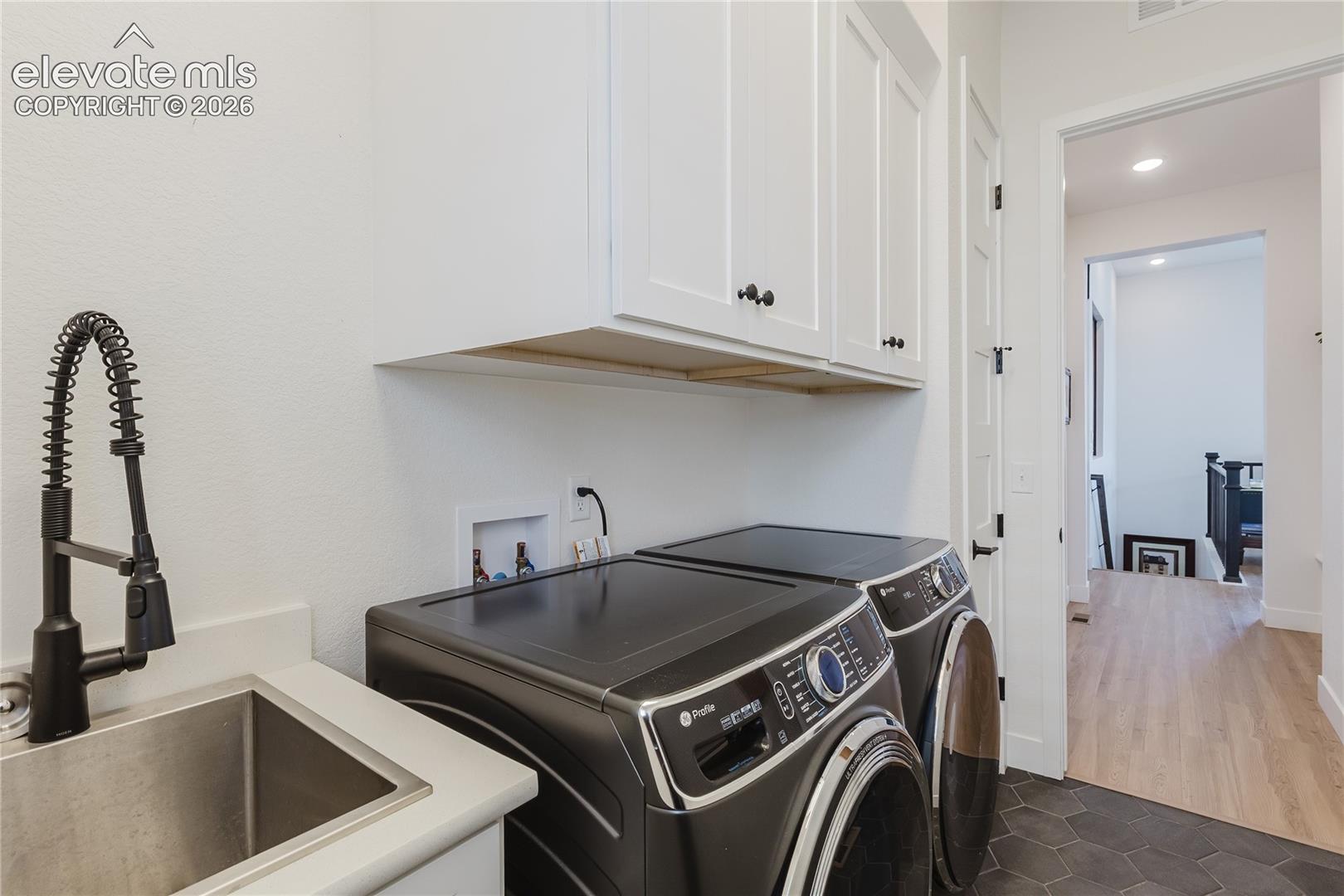 Laundry area featuring white cabinetry, a sink with a black spring faucet. (washer and dryer not included)