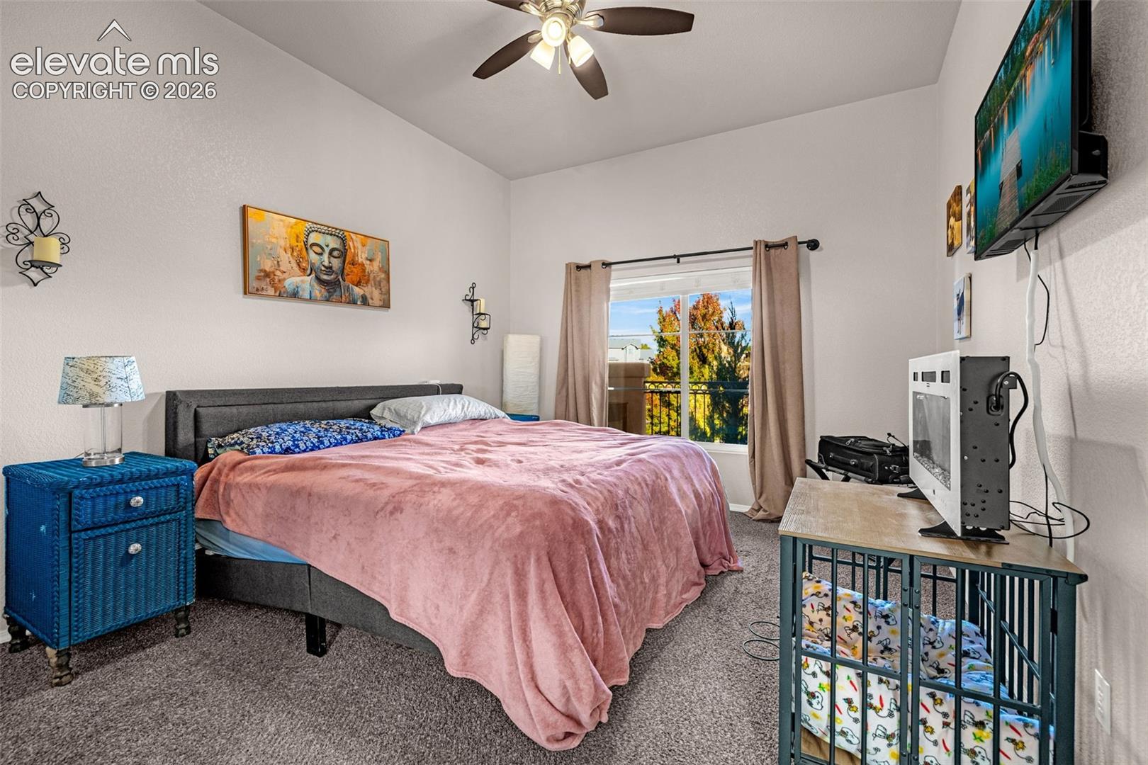 High-ceilinged room featuring neutral wall tones, carpeted flooring, a ceiling fan with integrated lighting, and a sliding glass door providing external access