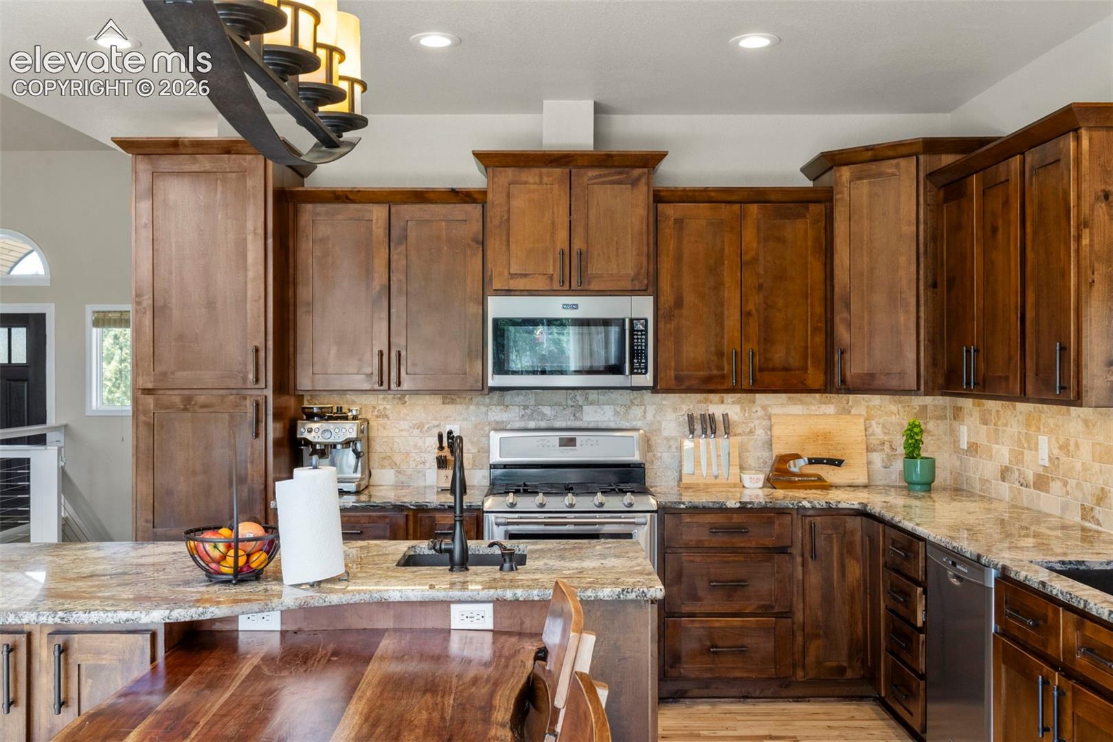 Kitchen featuring light stone countertops, stainless steel appliances, recessed lighting, tasteful backsplash, and light wood-type flooring