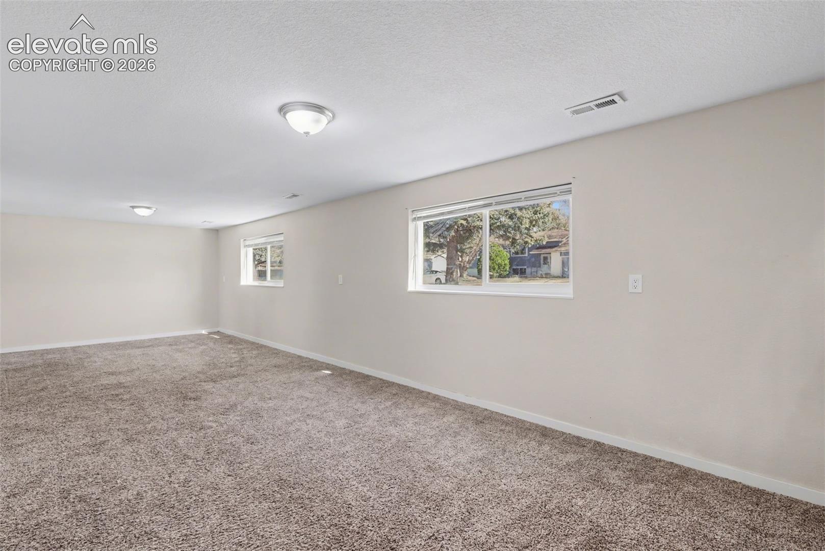 Spacious interior featuring wall-to-wall carpeting, neutral wall finishes, and dual sliding windows