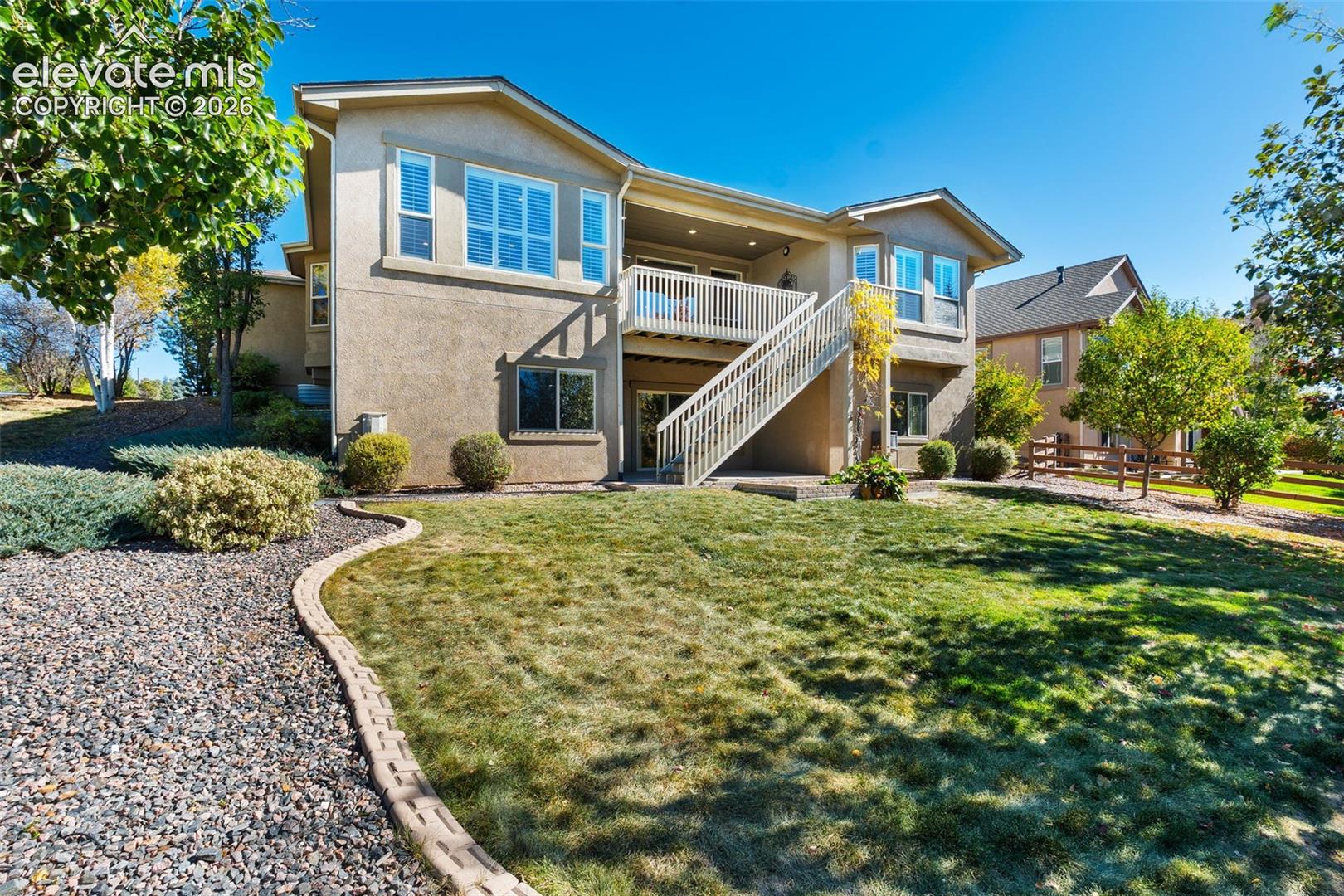 BACK OF HOME WITH LANDSCAPED LAWN & VIEW OF DECK AND PATIO FROM SIDE VIEW