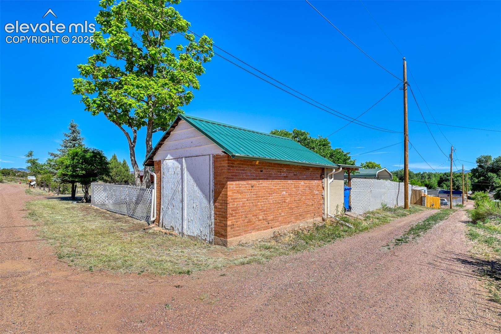Detached outbuilding featuring a red brick exterior, a green standing-seam metal roof, and white double-door entry