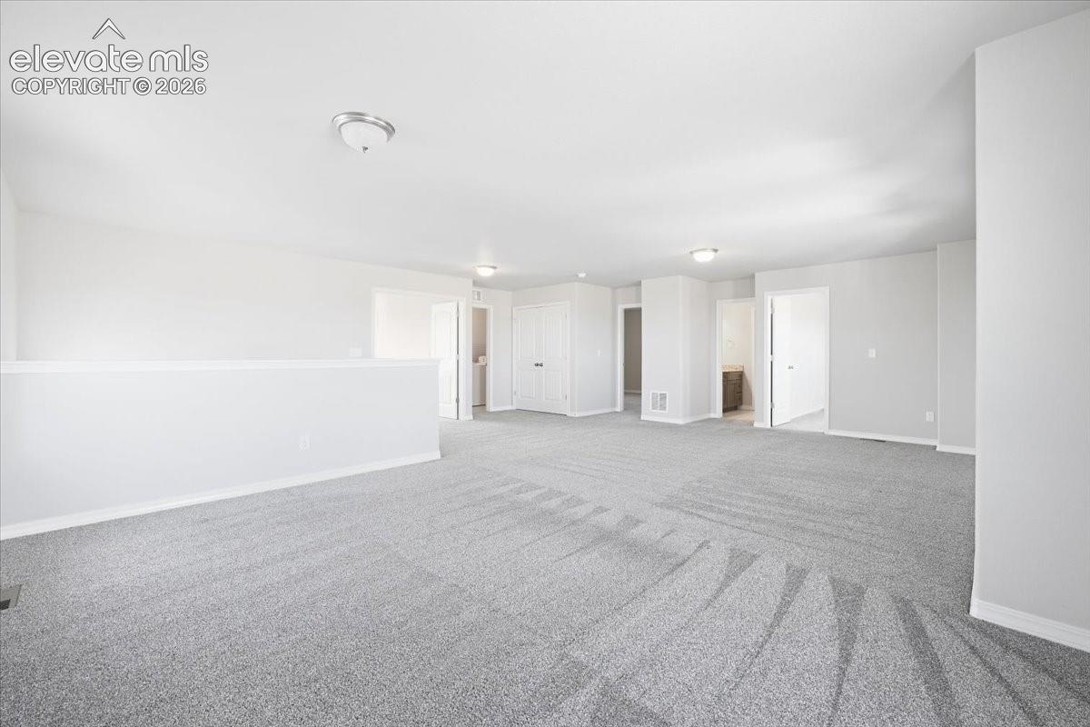 Neutral-toned wall-to-wall carpeting, crisp white walls, flush-mount ceiling lighting, and multi-panel interior doors