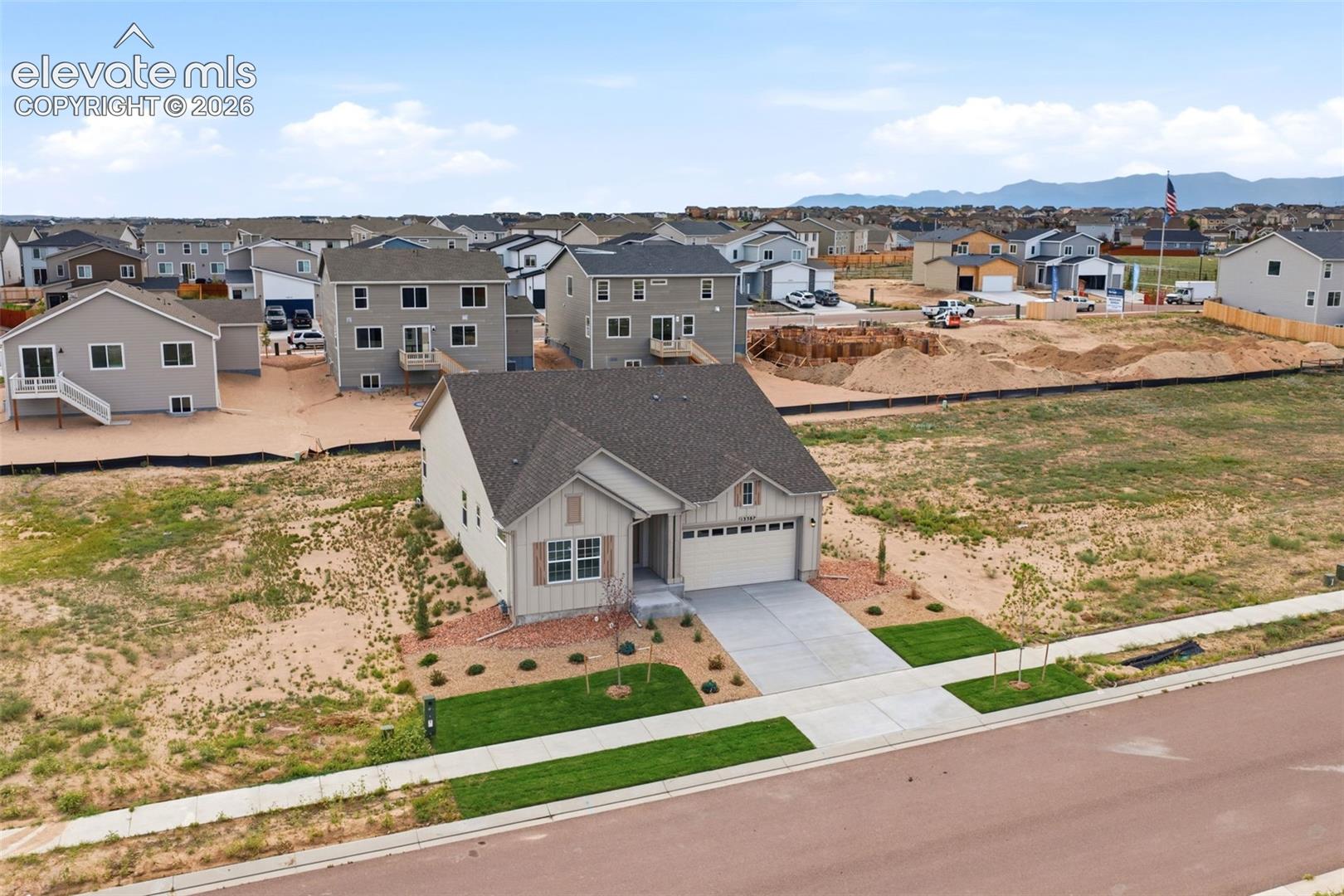 Single-family residence featuring a vertical siding exterior, asphalt shingle roof, two-car garage, concrete driveway, and xeriscaped front yard