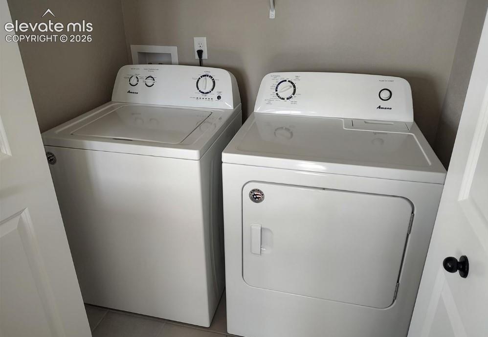Dedicated laundry area featuring a white top-load washer and side-by-side white dryer