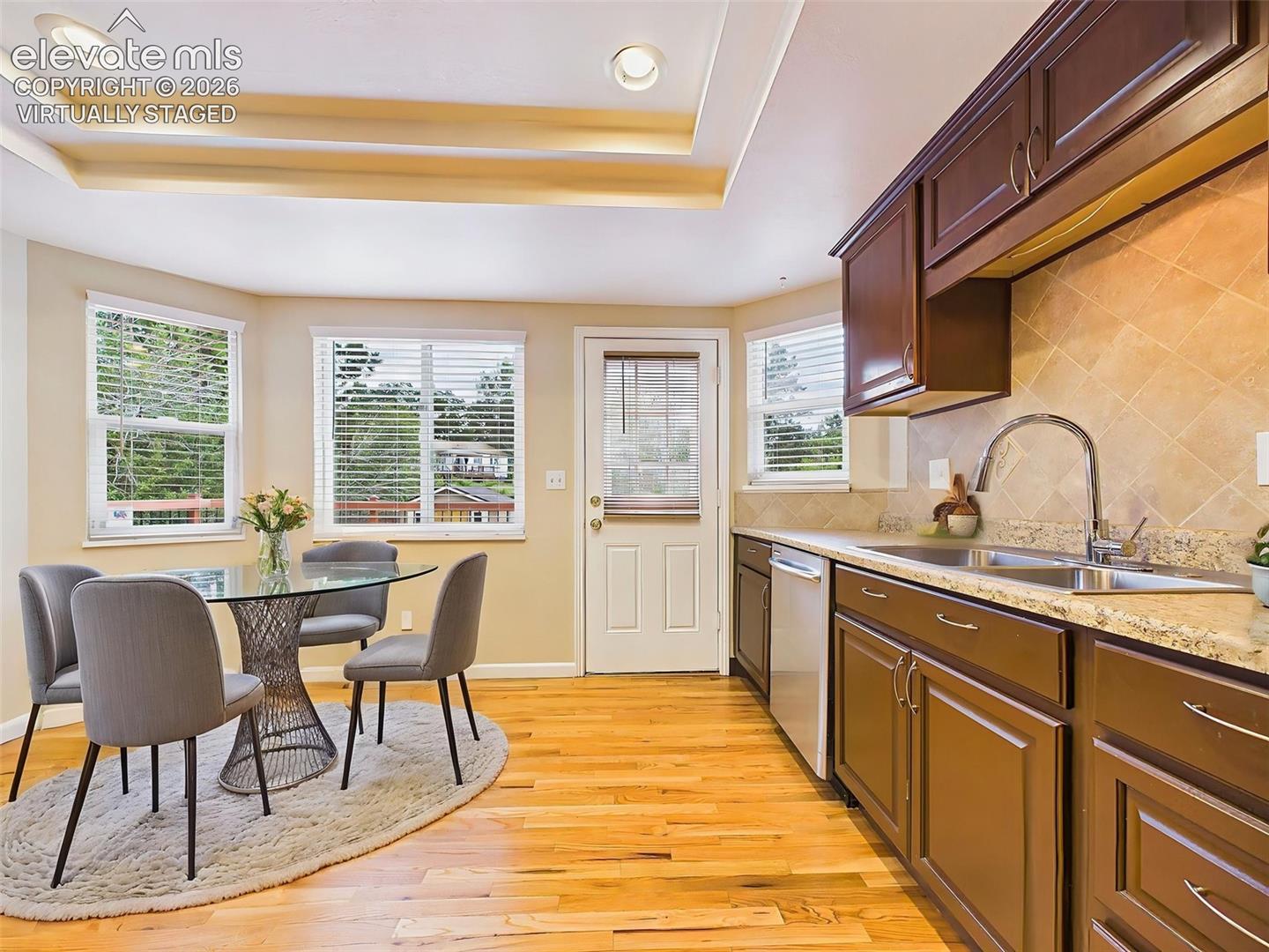 (Virtually Staged) Sunny breakfast nook surrounded by windows with direct access to the back deck. The kitchen offers abundant cabinetry, laminate countertops, stainless steel appliances, and a functional layout.