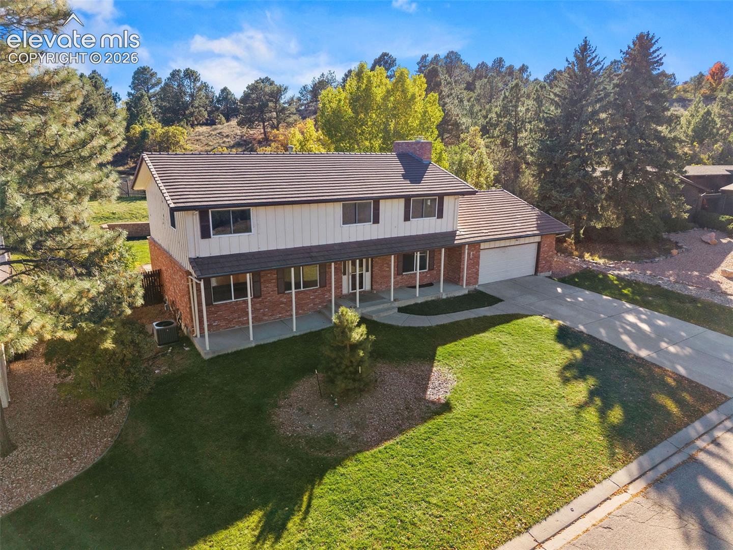 Two-story residence featuring brick and vertical siding exterior, tiled roof, covered front porch, and attached garage