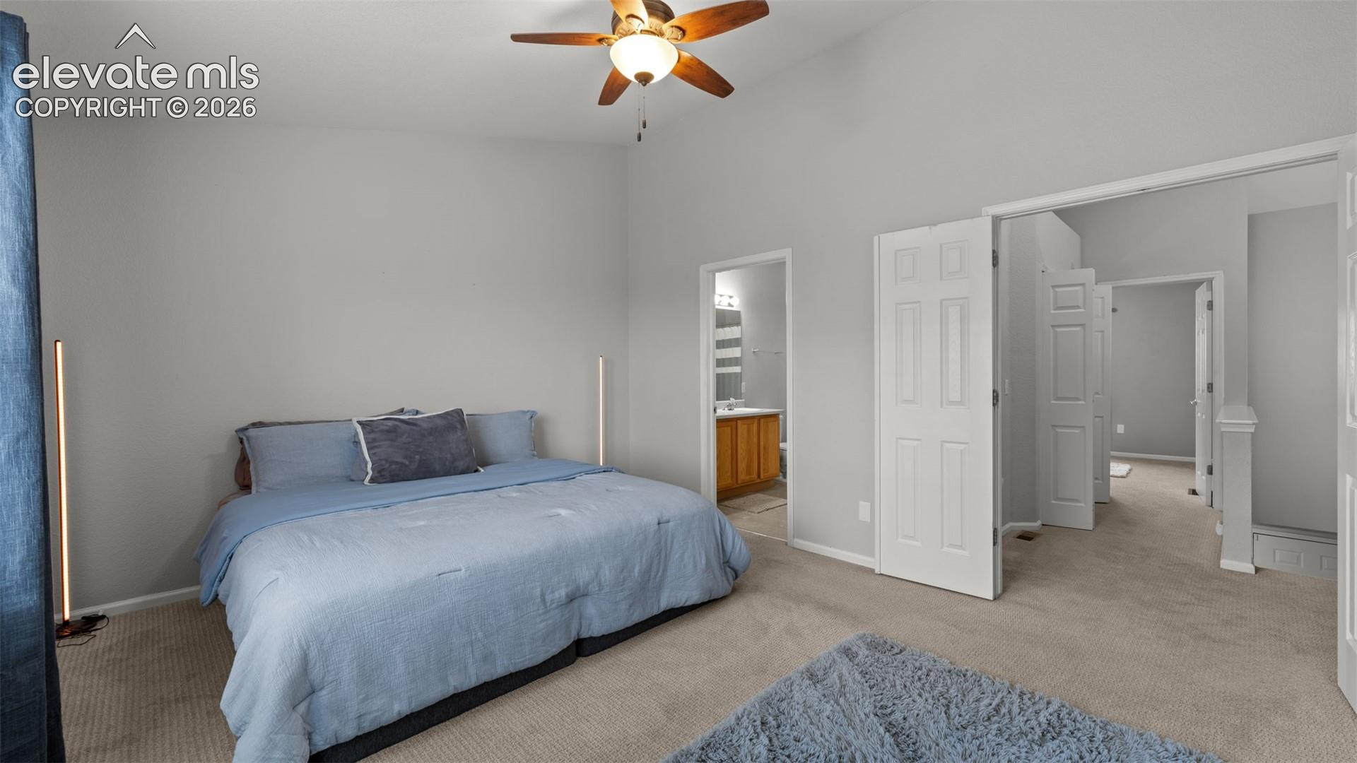 Vaulted ceilings with a central paddle ceiling fan and neutral carpeting
