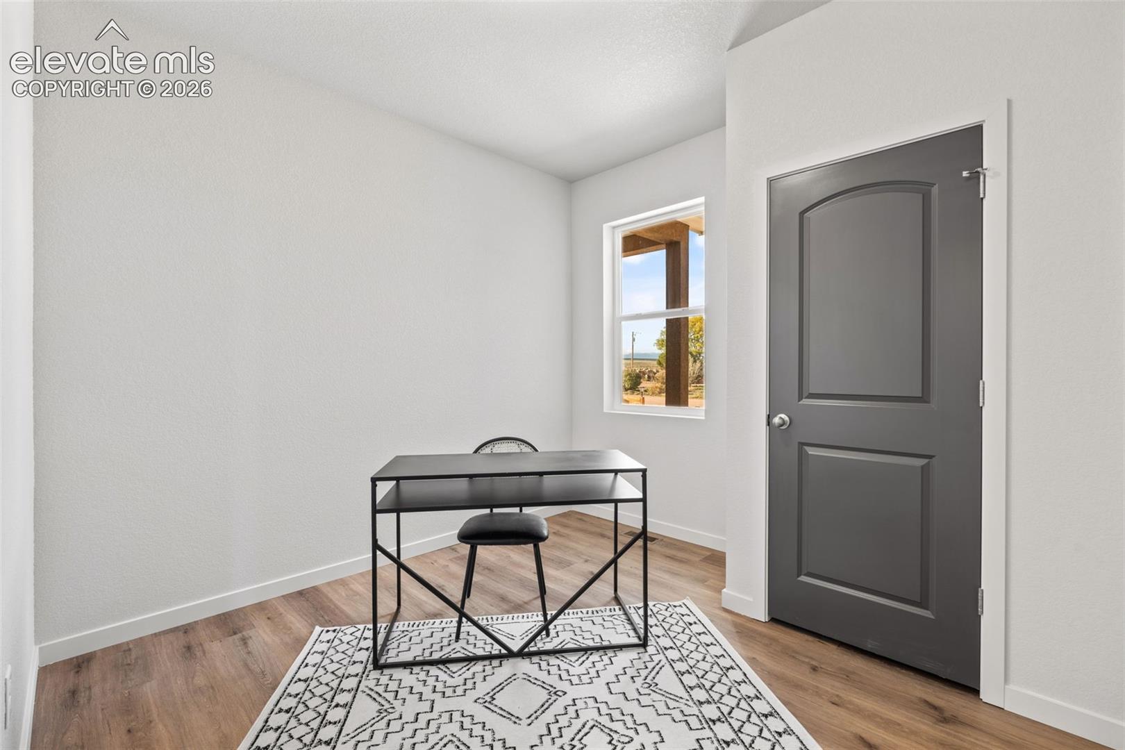 Wood-finish flooring, white painted walls, and a window with natural light