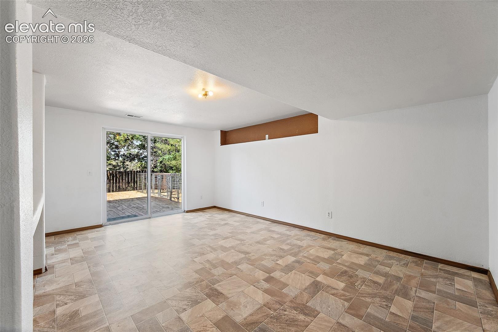Spacious room featuring tile-finish flooring and a glass sliding door providing outdoor access