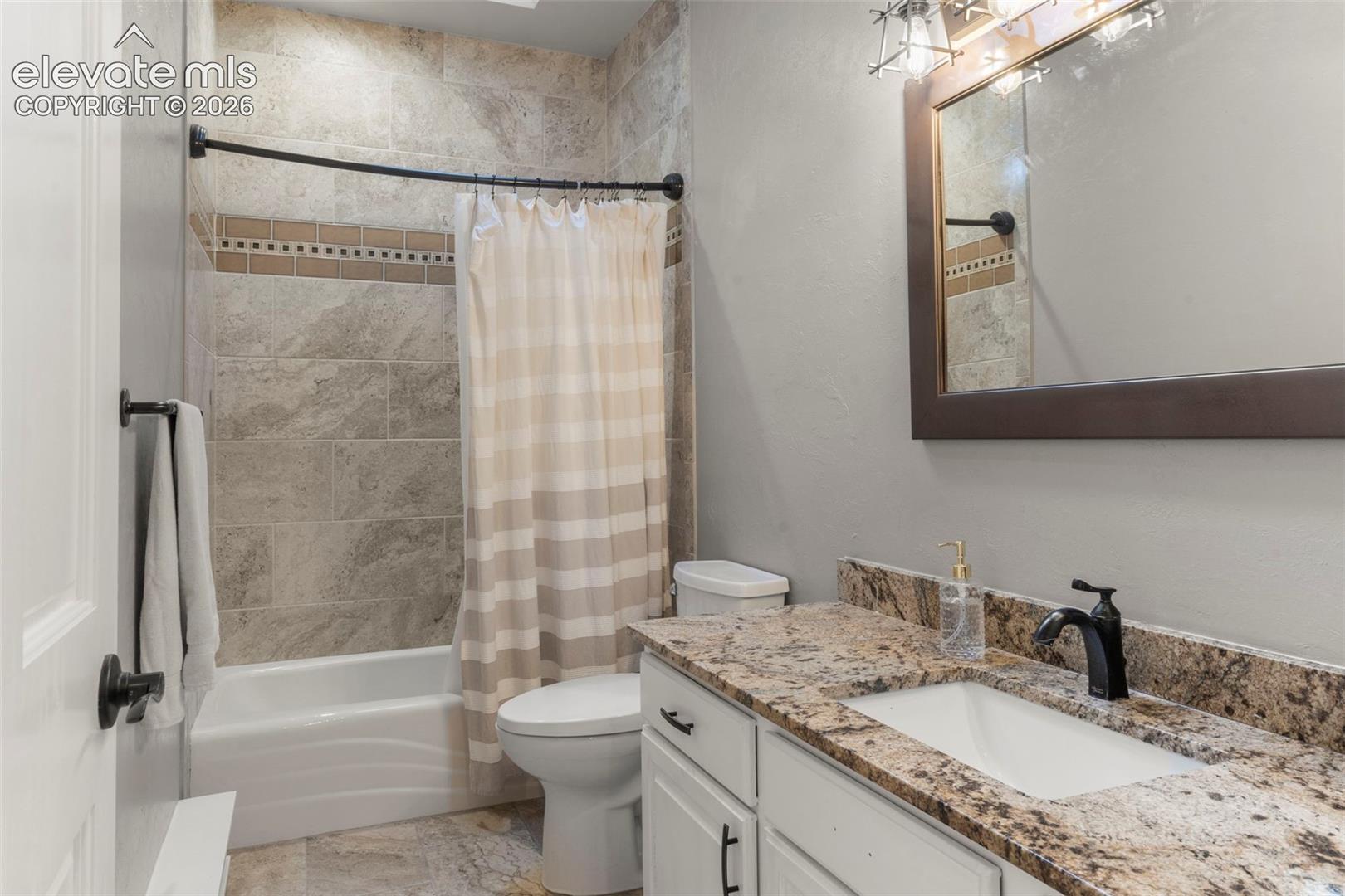 Full bath with shower / tub combo with curtain and vanity