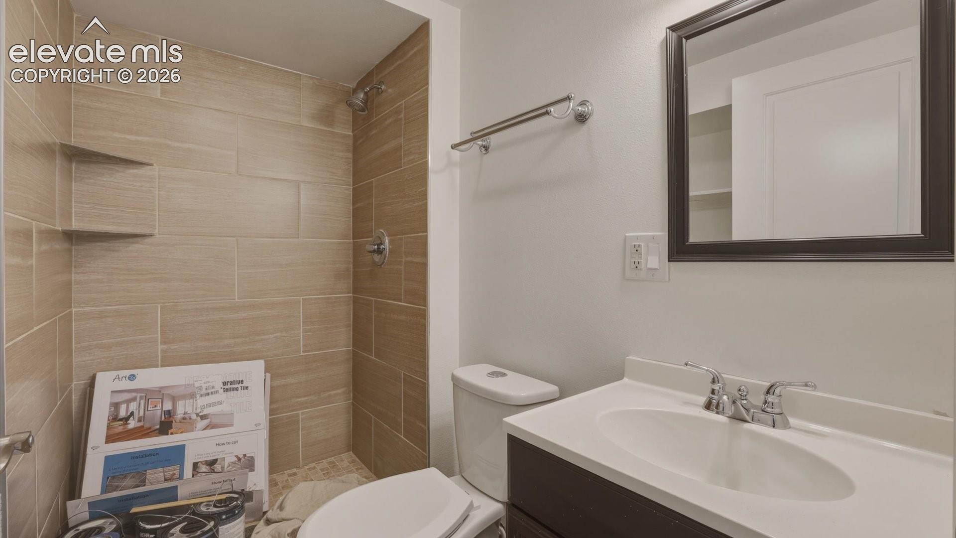 Lower Level Shower Bathroom with vanity, framed mirror, and tiled shower.