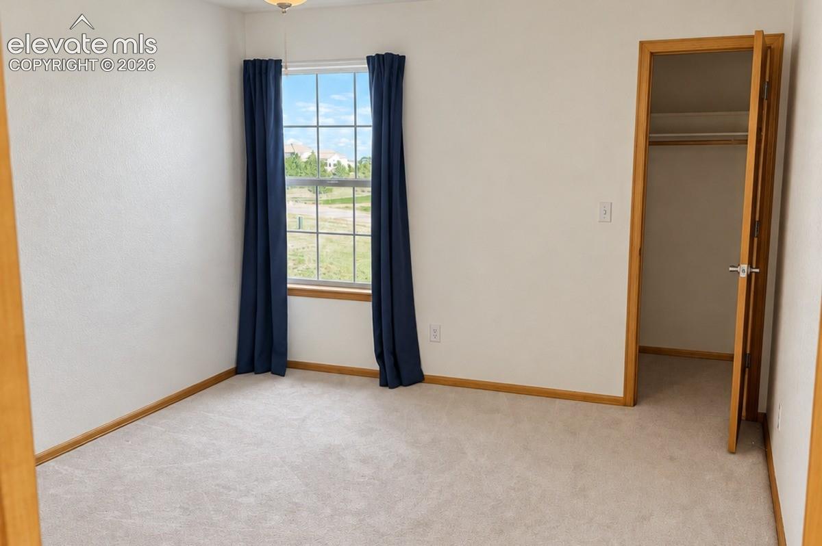 Upstairs bedroom 2/3. Neutral-toned walls complement the light-colored carpeting & walk-in closet. No staging.