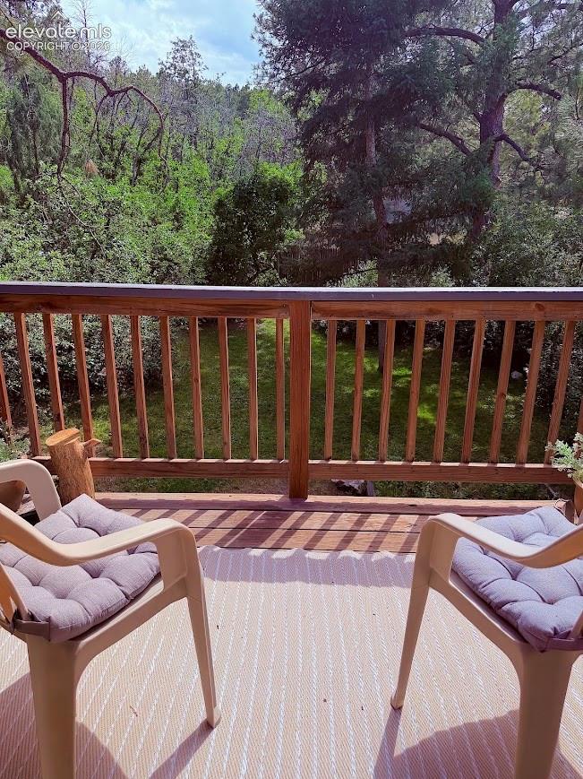 Expansive outdoor deck featuring wood railing and a tree-lined backdrop