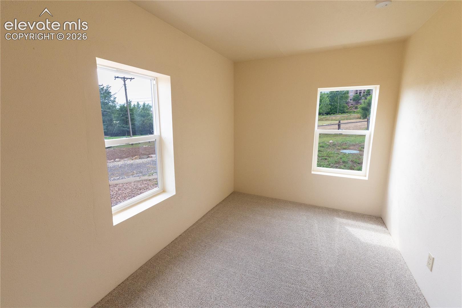 Interior space featuring neutral wall tones, wall-to-wall carpeting, and two double-hung windows