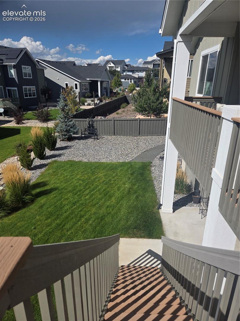 Expansive green lawn, gravel landscaping, established trees and shrubs, privacy fencing, and concrete patio