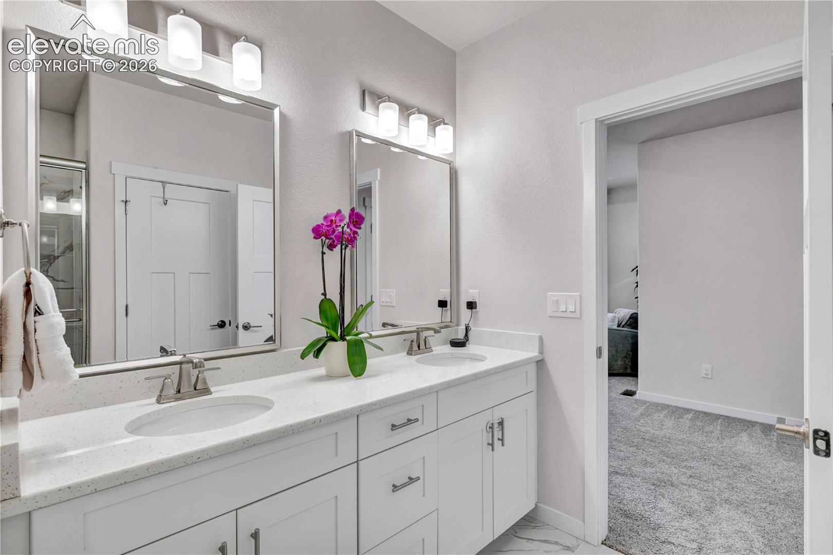 Dual-sink vanity with white cabinetry, quartz countertop, and polished chrome fixtures