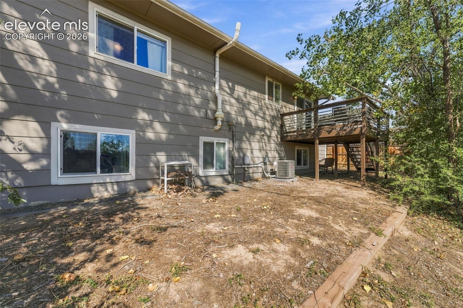 Two-story exterior with horizontal siding, multiple windows, and a raised wooden deck with railings