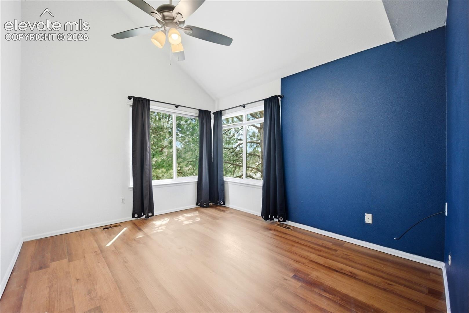 Vaulted ceilings, wood-finish flooring, dual windows, and a ceiling fan with integrated lighting