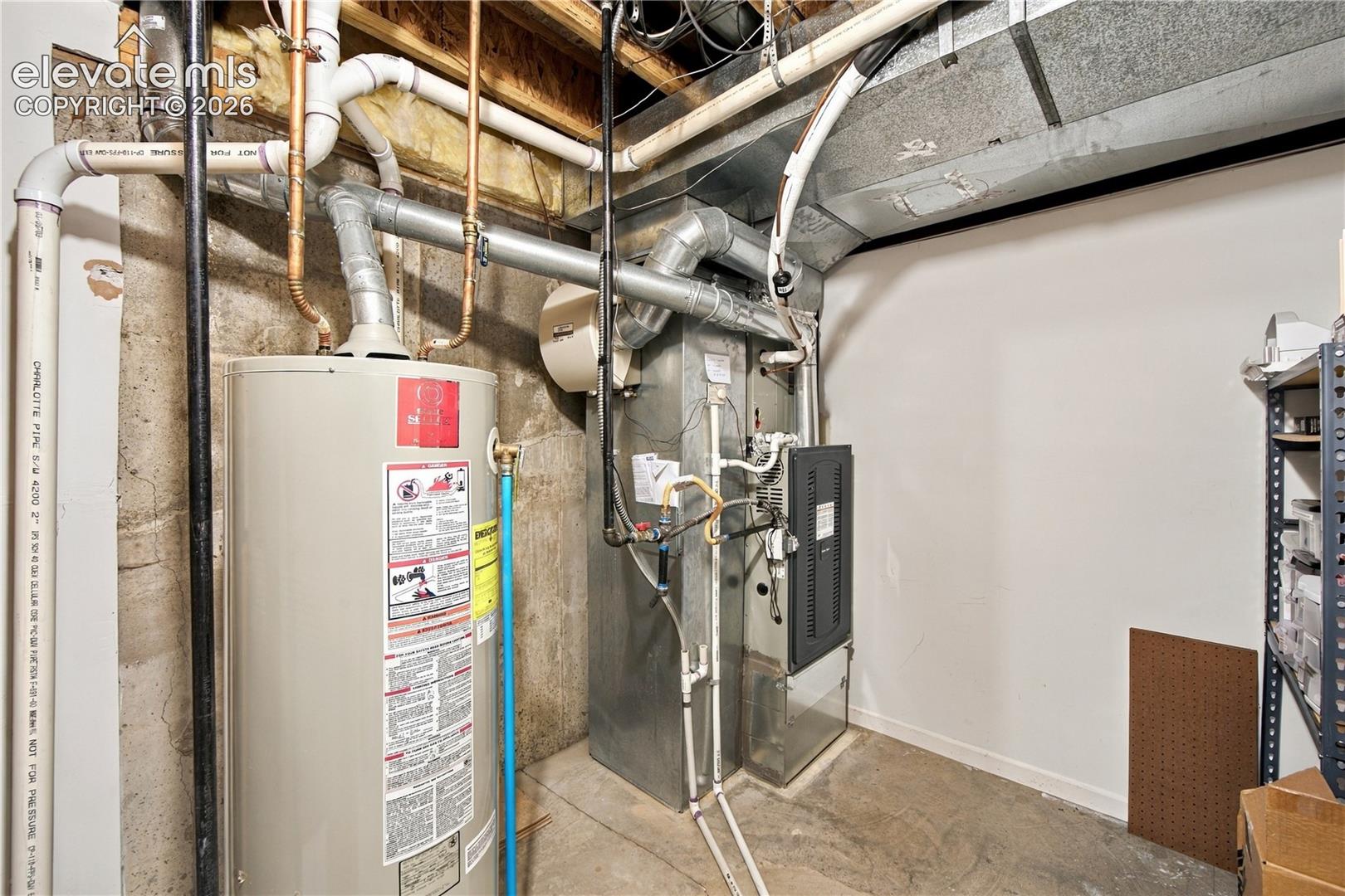 Mechanical area featuring a vertical water heater, gas furnace, and exposed HVAC ductwork against a concrete foundation wall
