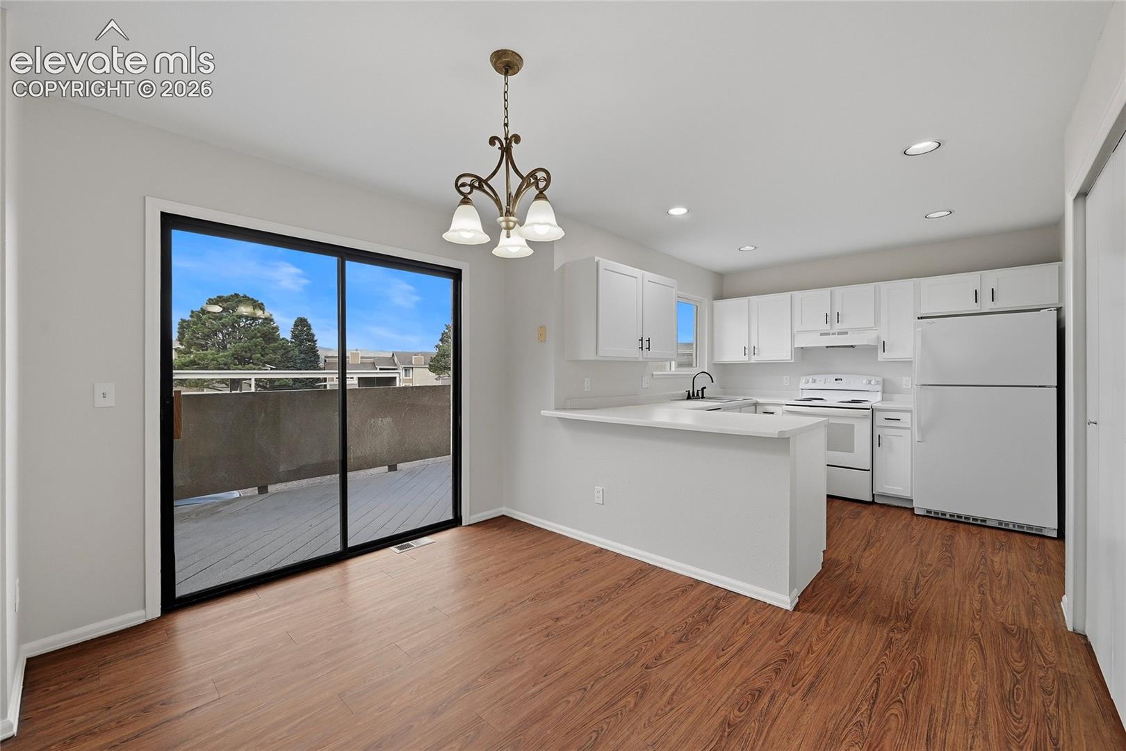Kitchen featuring white cabinetry, wood-finish flooring, recessed lighting, a breakfast bar, and a sliding glass door