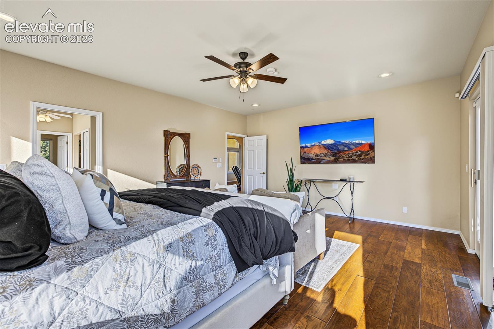 Additional view of the spacious primary bedroom featuring hardwood flooring, a ceiling fan, recessed lighting, mountain views, and sliding glass doors leading to the rear deck.
