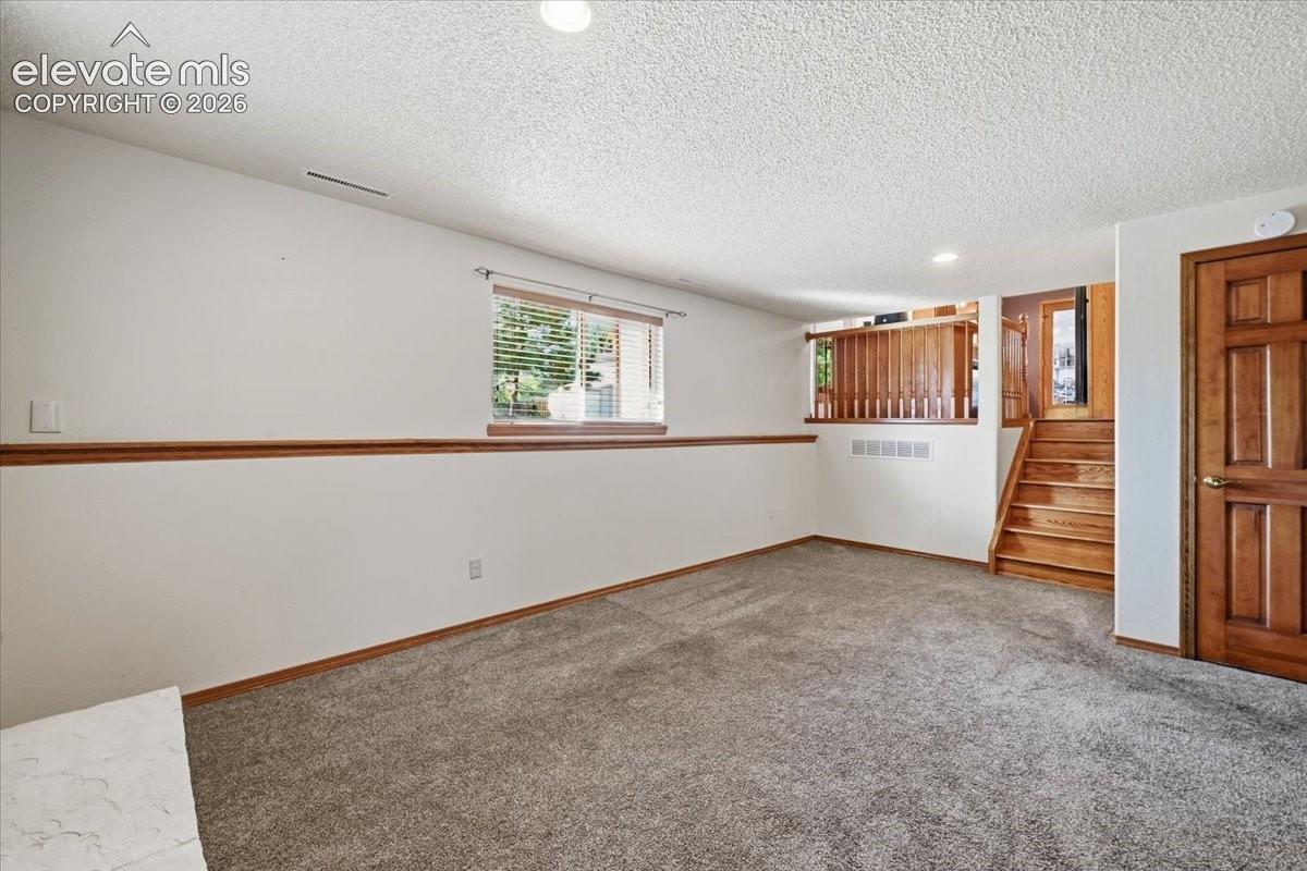 Recessed ceiling lighting, wood-finish trim, wall-to-wall carpeting, wood-finish staircase, and panel-style interior door