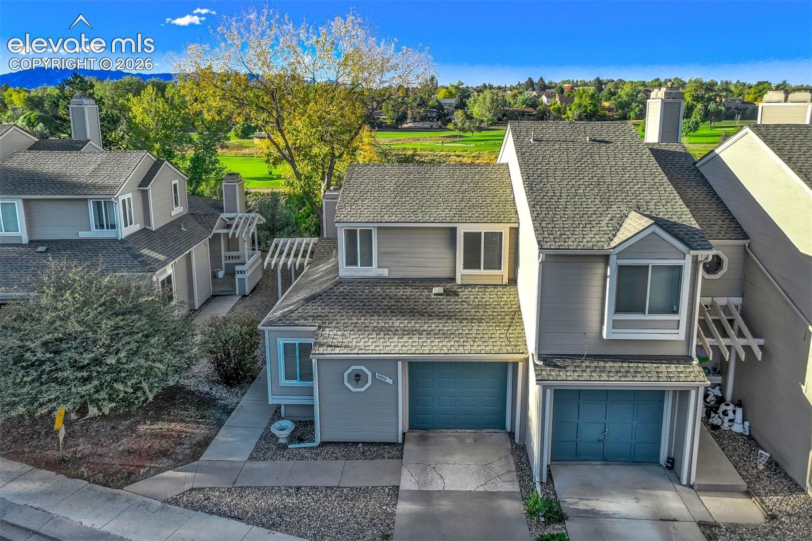 Multi-level exterior featuring light gray siding, asphalt shingle roofing, dual attached garages, and pergolas
