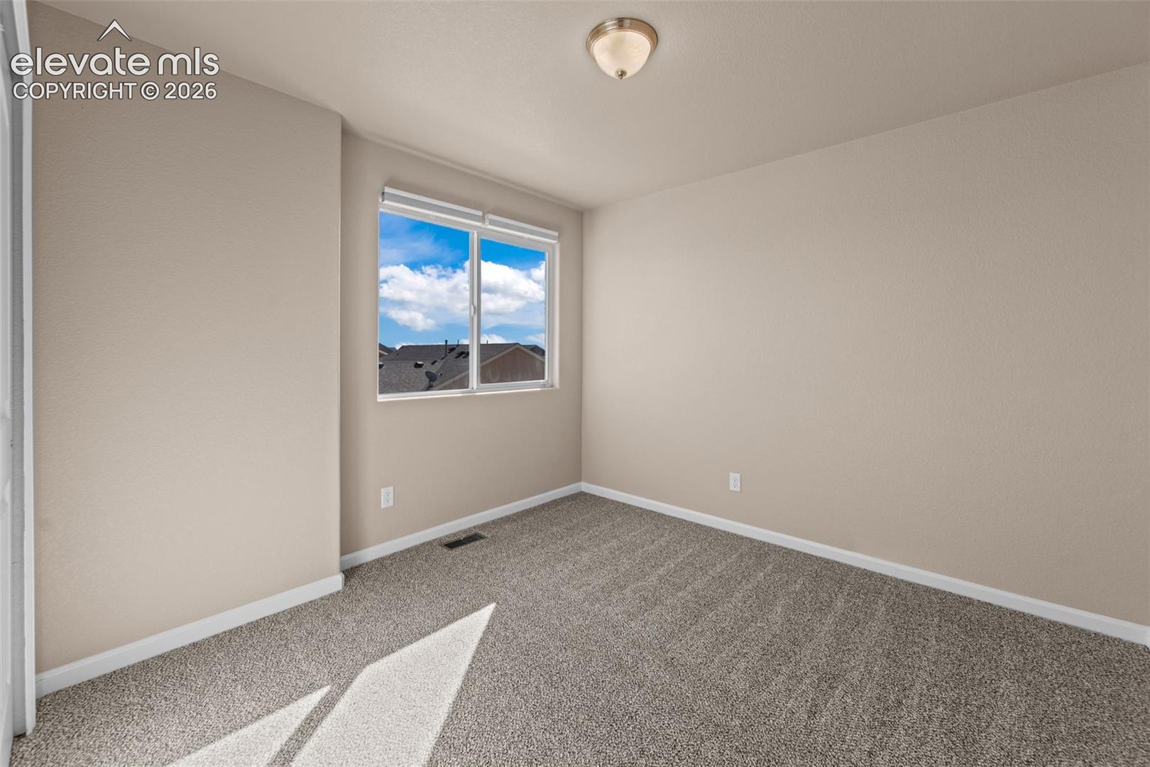 Room featuring neutral wall tones, carpeted flooring, a single-pane sliding window, and a flush-mount ceiling light fixture