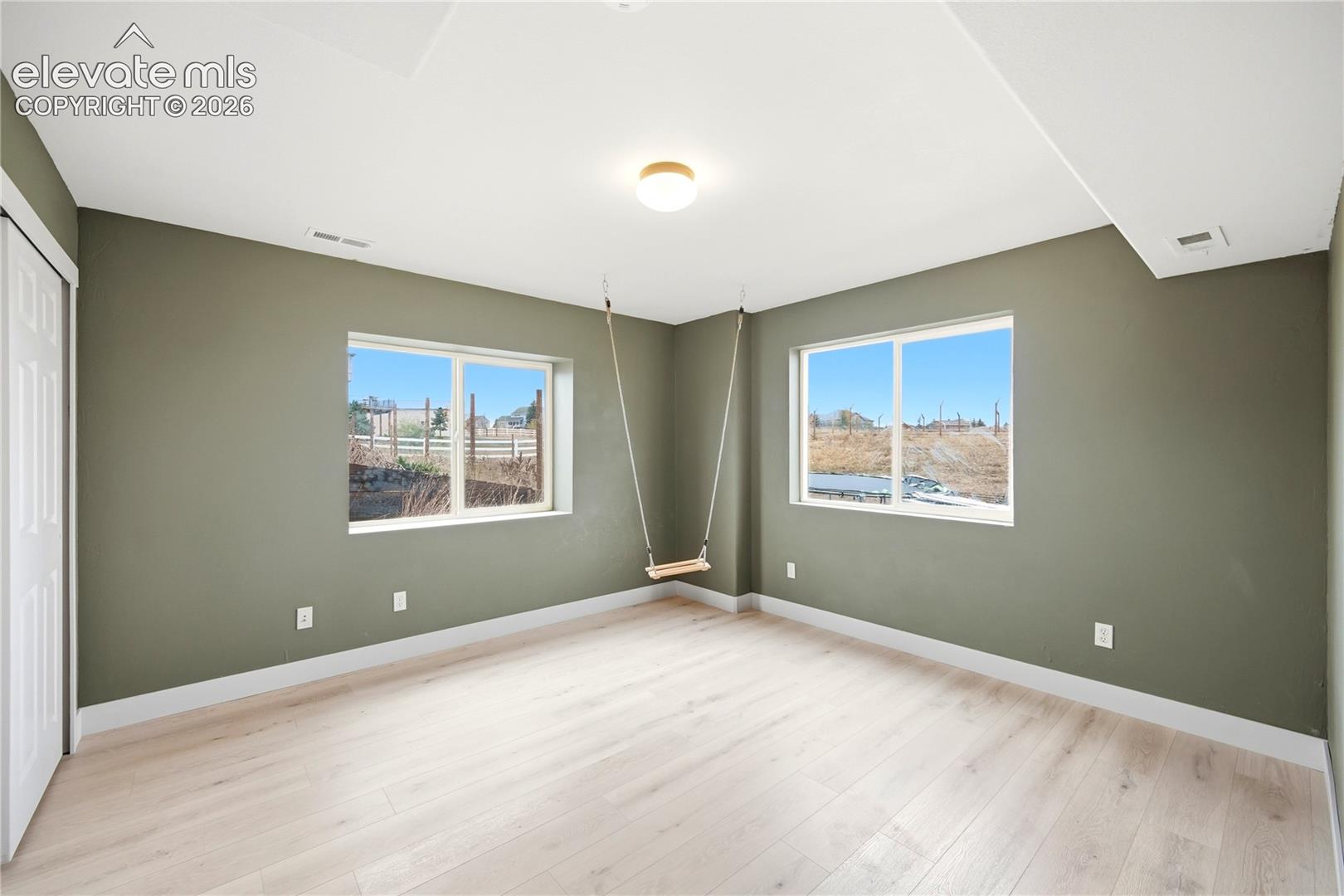 Room featuring wood-finish flooring, dual sliding windows, and a ceiling-mounted light fixture