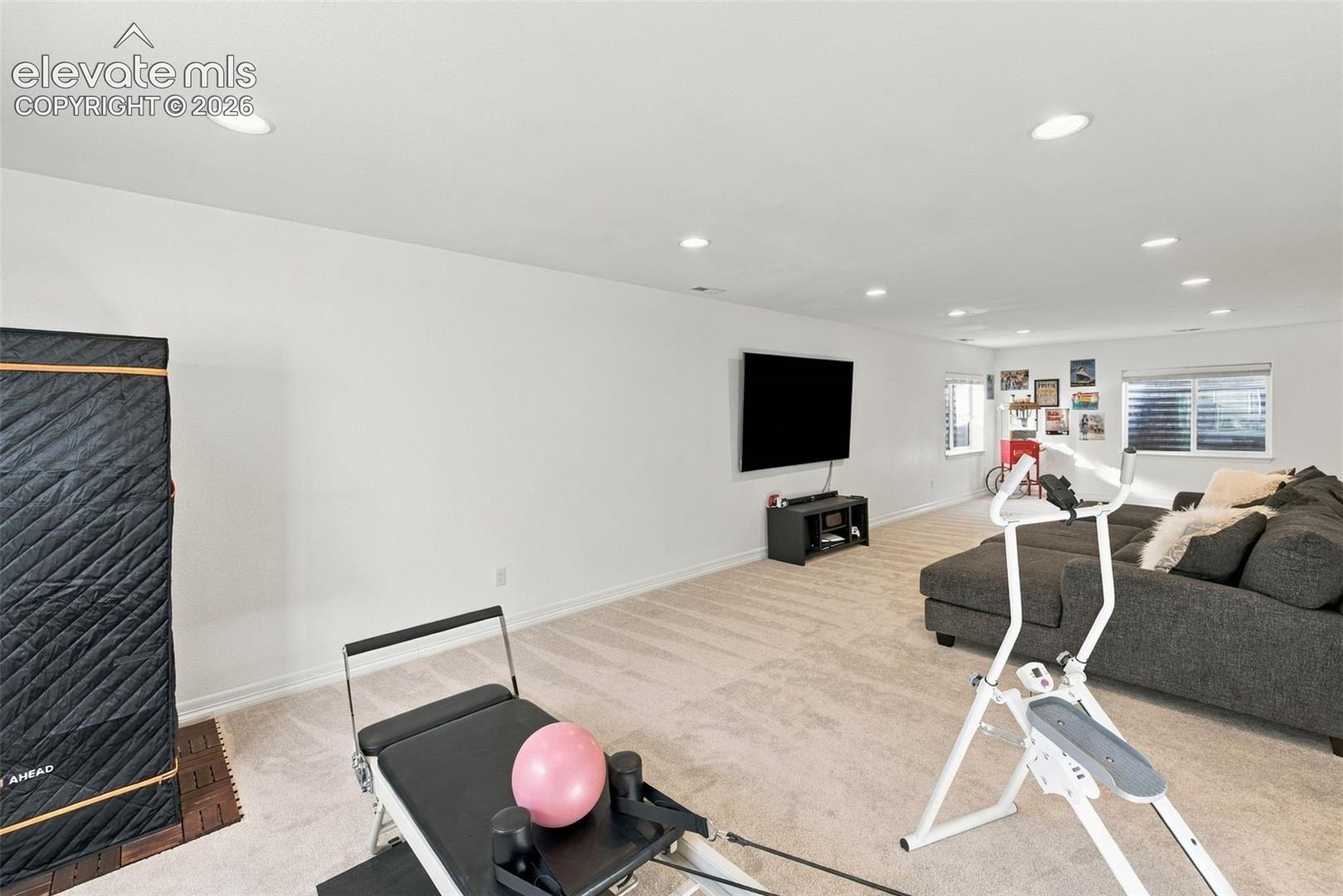 Expansive interior space featuring neutral wall-to-wall carpeting, recessed ceiling lighting, and multiple windows with horizontal blinds