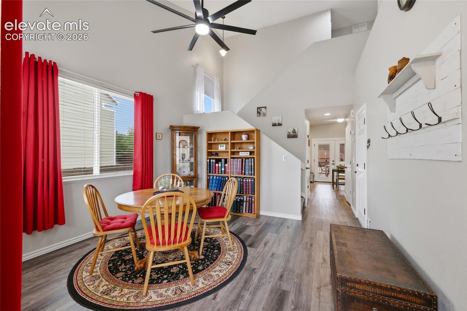 Vaulted ceilings with a ceiling fan, wood-finish flooring, built-in shelving, and white interior doors