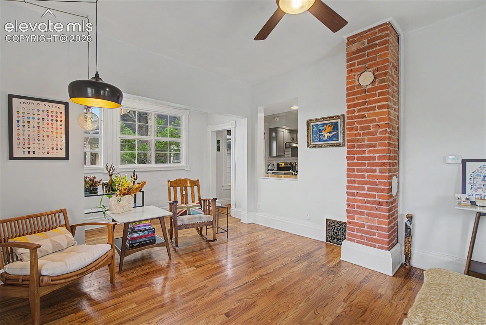 Living area featuring hardwood flooring, exposed brick, and natural lighting